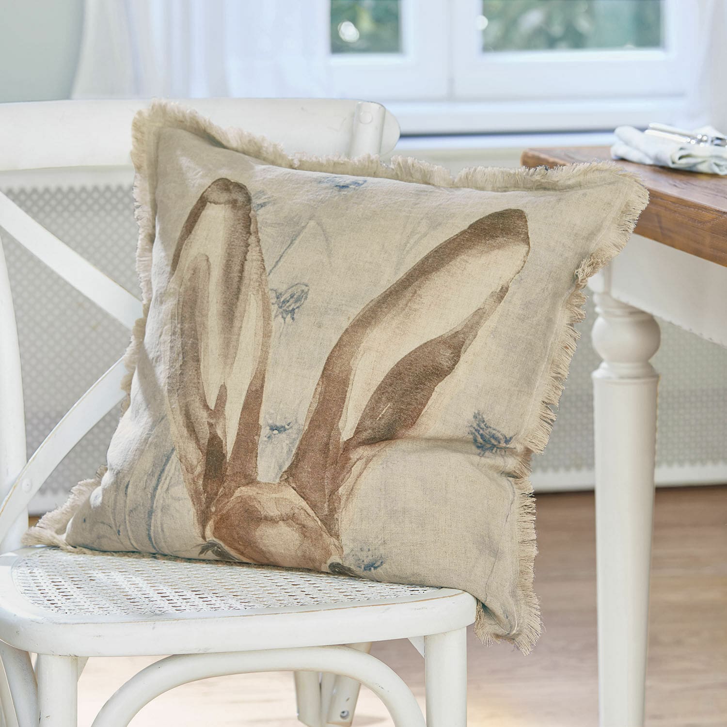 Kussenhoes Kameron Beige linnen kussen met konijnenorenprint op witte stoel voor interieurdecoratie