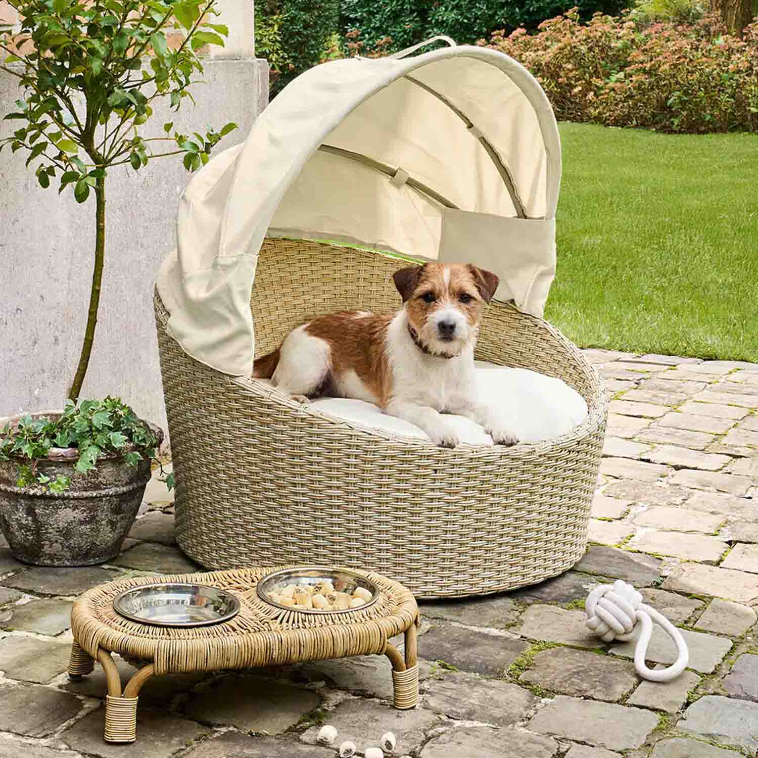 Ronde hondenmand van beige rattan met crèmekleurig dak en kussen voor buiten