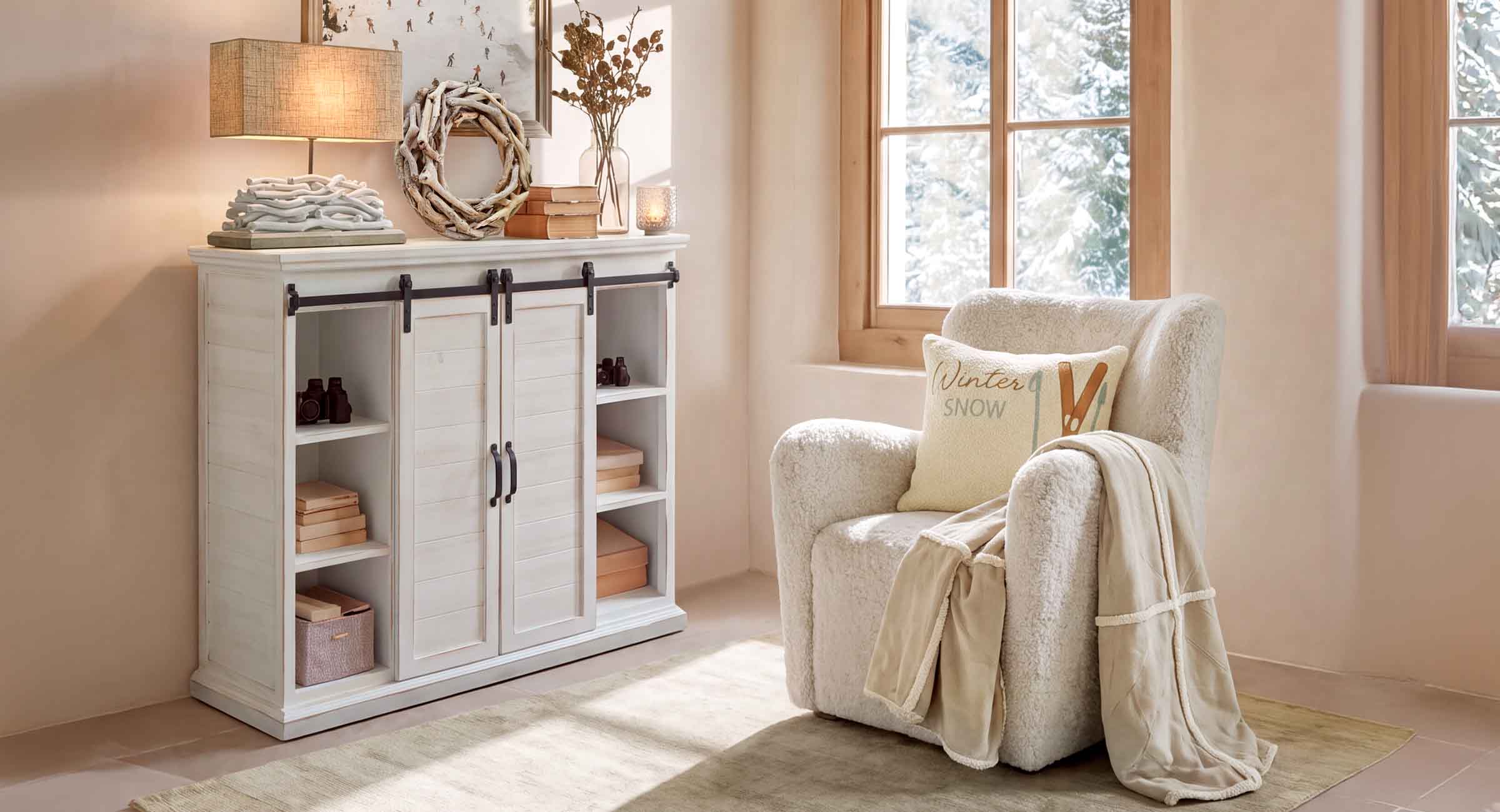 Gezellige hoek met witte pluche fauteuil en lichte houten kast in lichte kamer met winteruitzicht