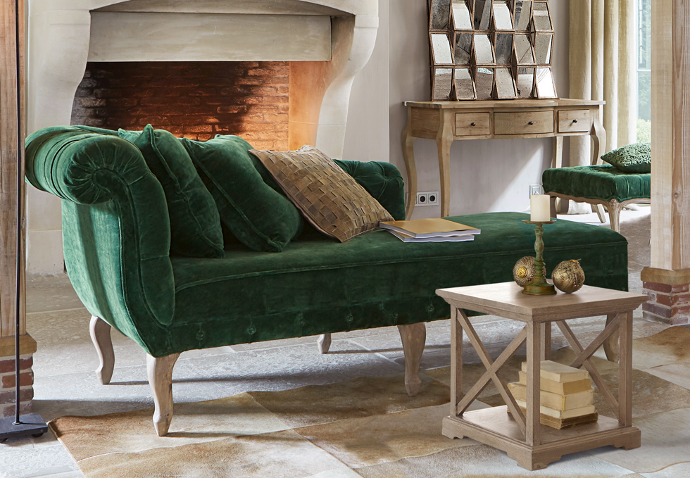 Klassieke groene fluwelen bank met houten poten in elegante woonkamer met open haard