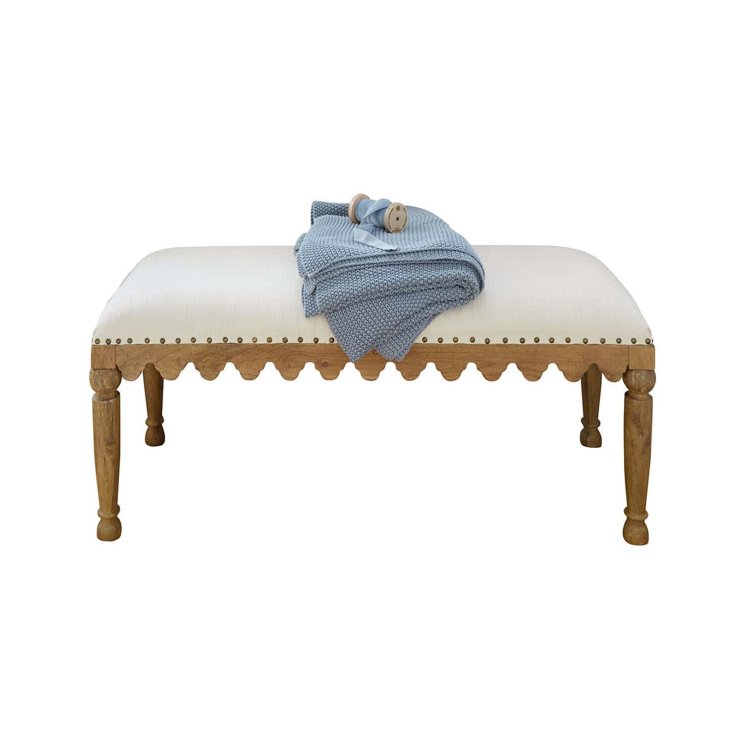 Gestoffeerde bank met lichte stof en houten frame, met blauwe gebreide deken erop