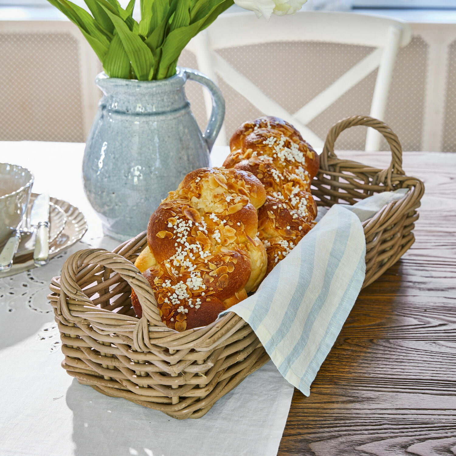 Mand Balmis Rieten mand met twee handvatten met gevlochten brood en linnen doek op houten tafel