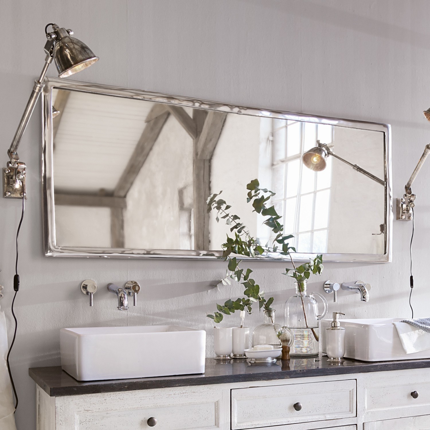 Grote rechthoekige spiegel met metalen lijst boven witte wastafel op zwart blad in badkamer