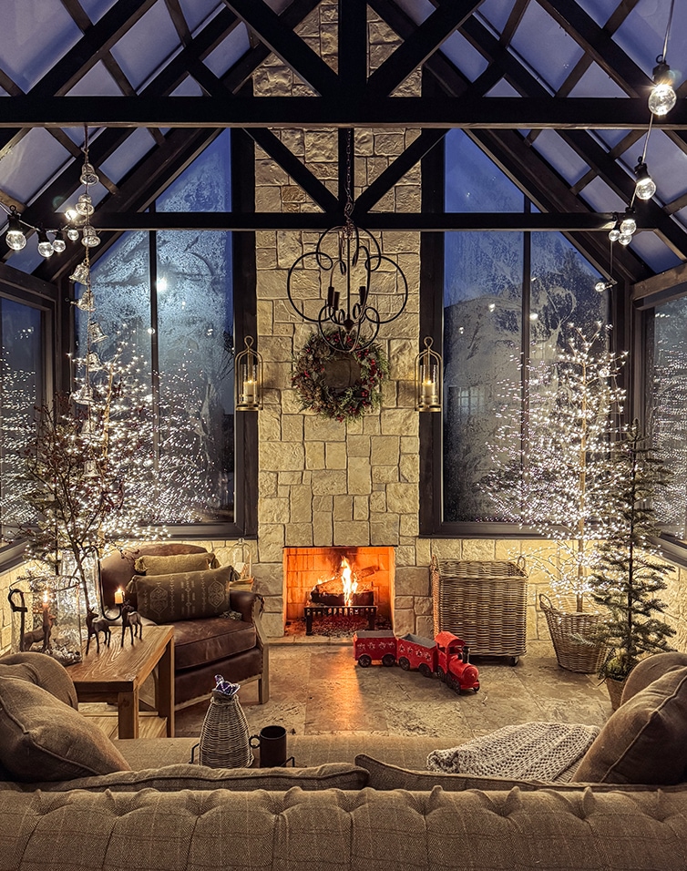 Gezellige woonkamer met open haard, kerstdecoraties en LED-verlichting in een oranjerie van steen en hout