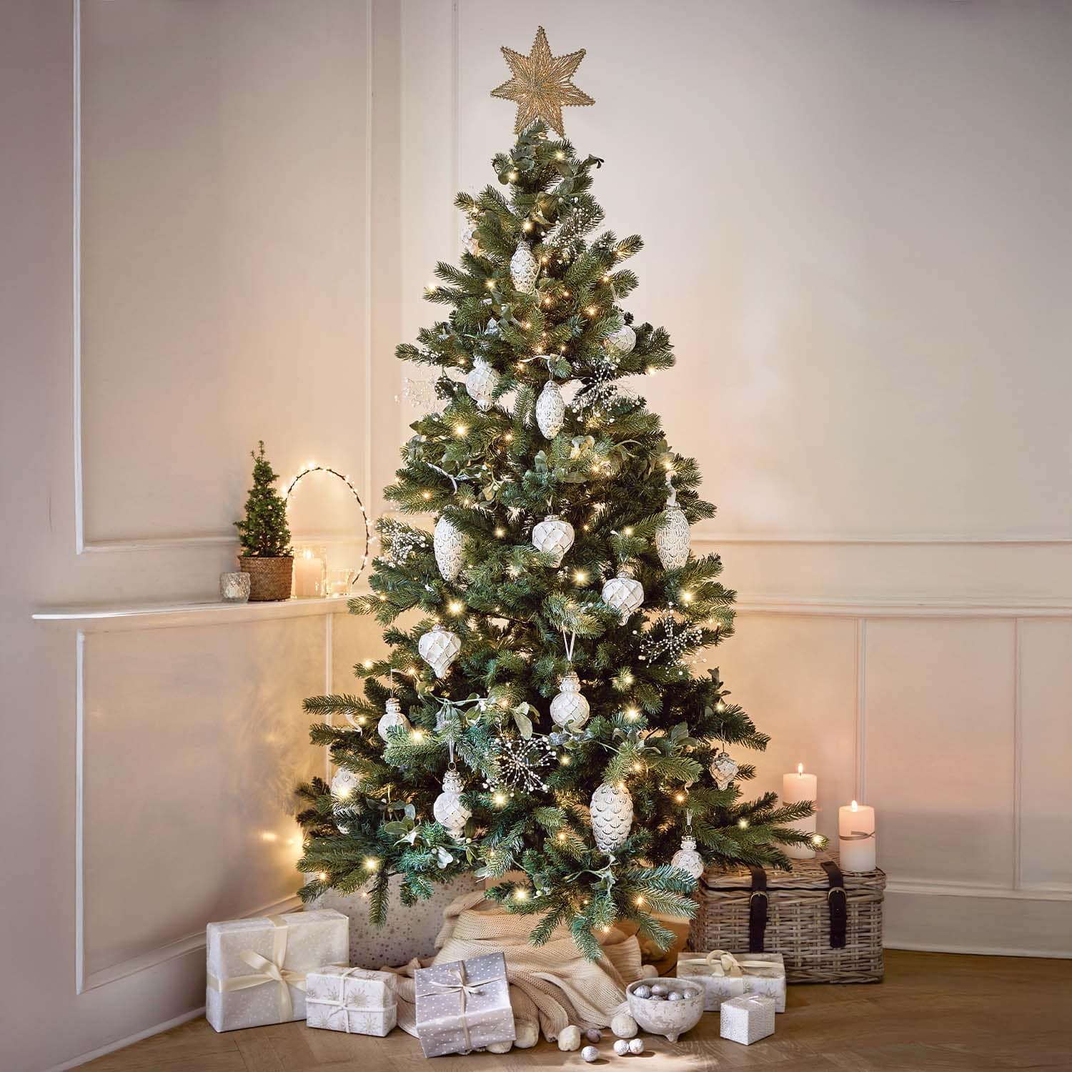 Kerstboom versierd met witte ballen en lichtjes, cadeaus en kaarsen in een gezellige kamer
