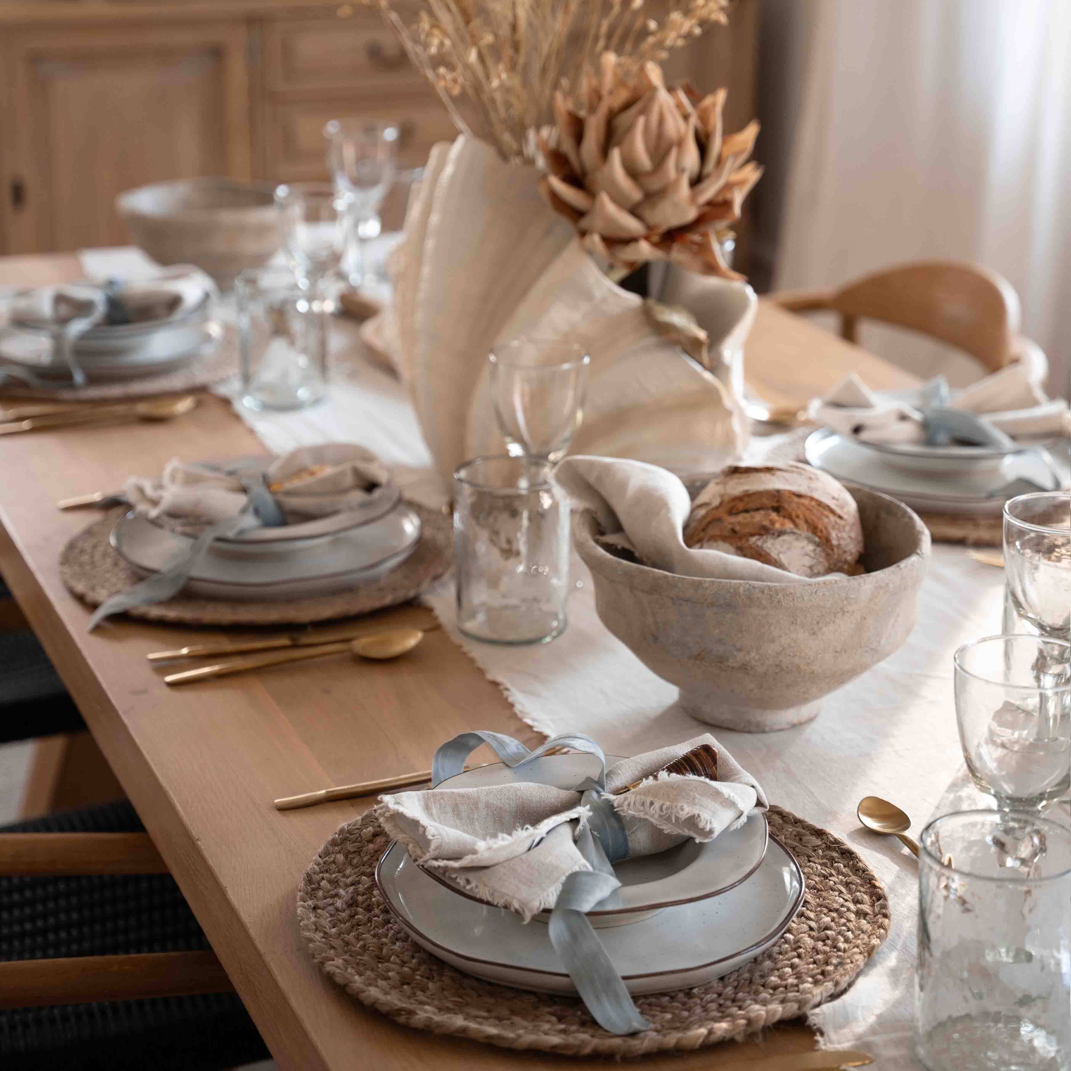 Tafeldecoratie met natuurlijke schelp en brood in linnen kom op houten tafel