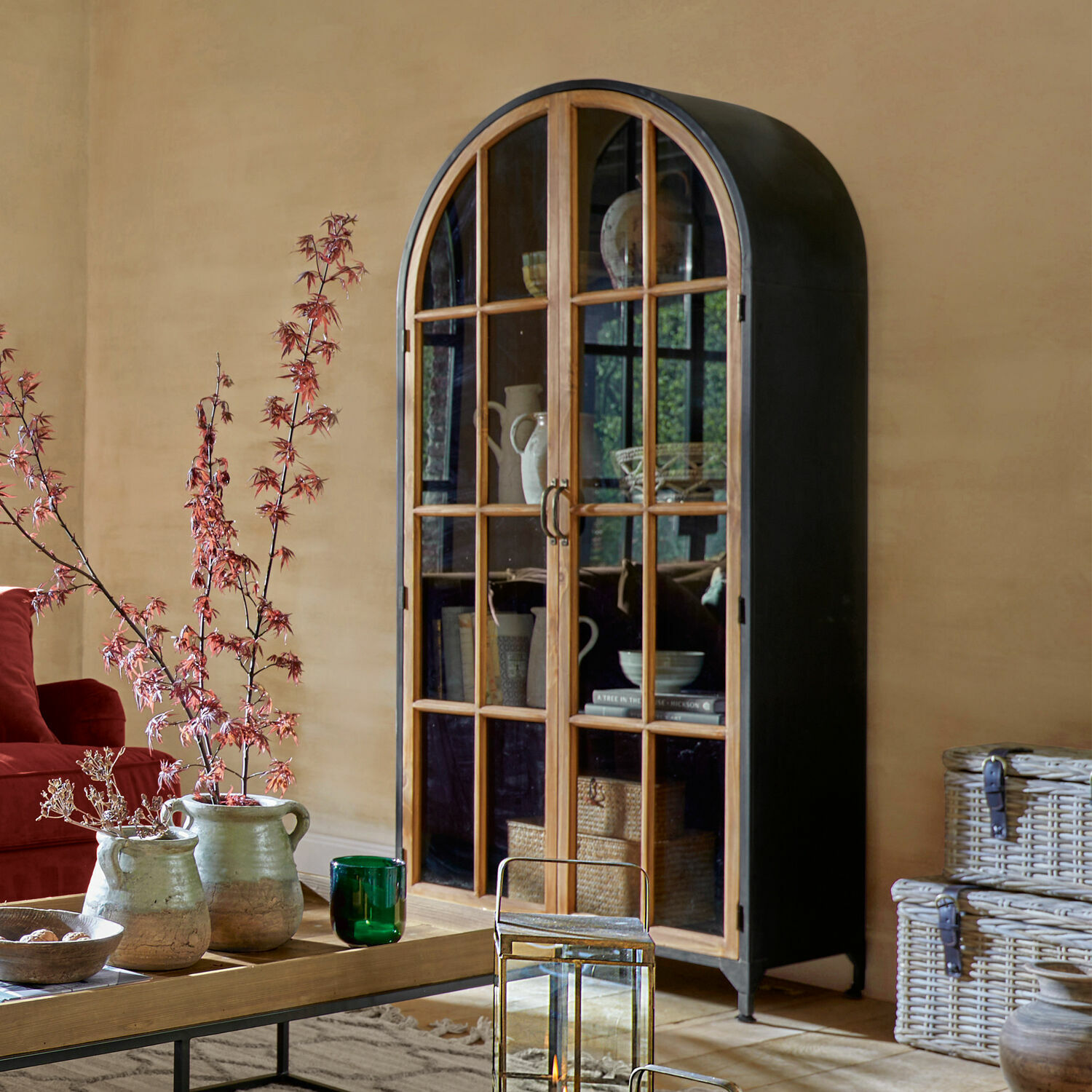 Kast met afgerond zwart metalen frame en houten deuren met glas in een woonkamer