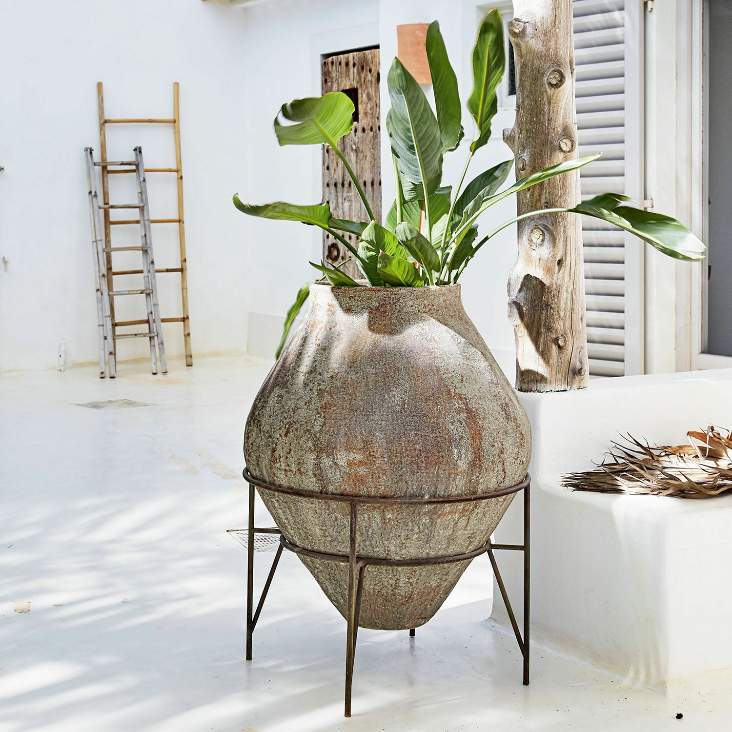 Vaas Pive Grote stenen pot op metalen standaard met groene plant in lichte, minimalistische ruimte