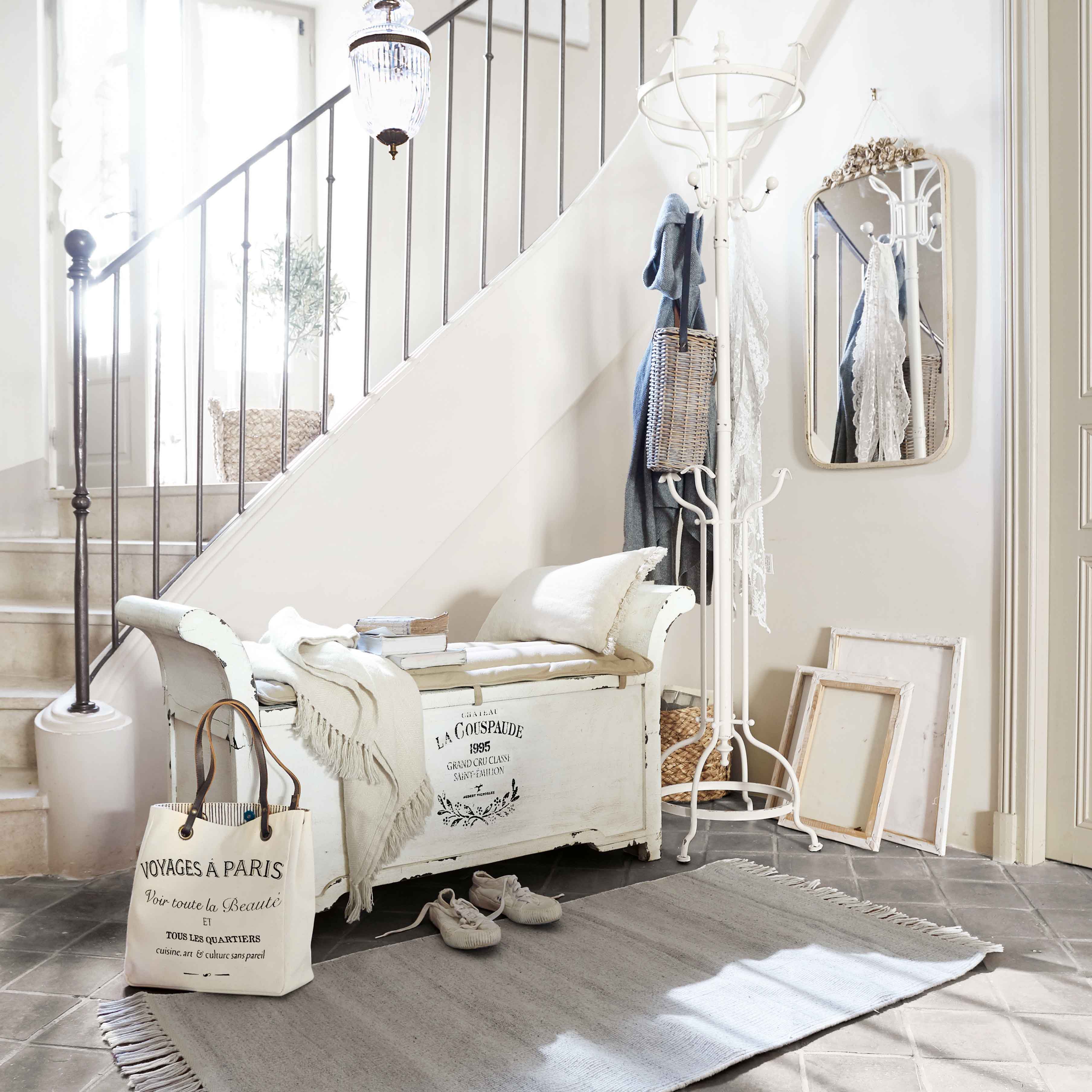 Witte houten bank met kussen en deken in lichte hal met kapstok en spiegel