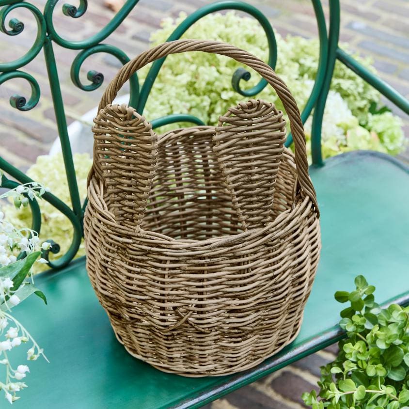 Natuurlijke rieten mand met oren op groene bank, decoratieve opbergmand voor buiten