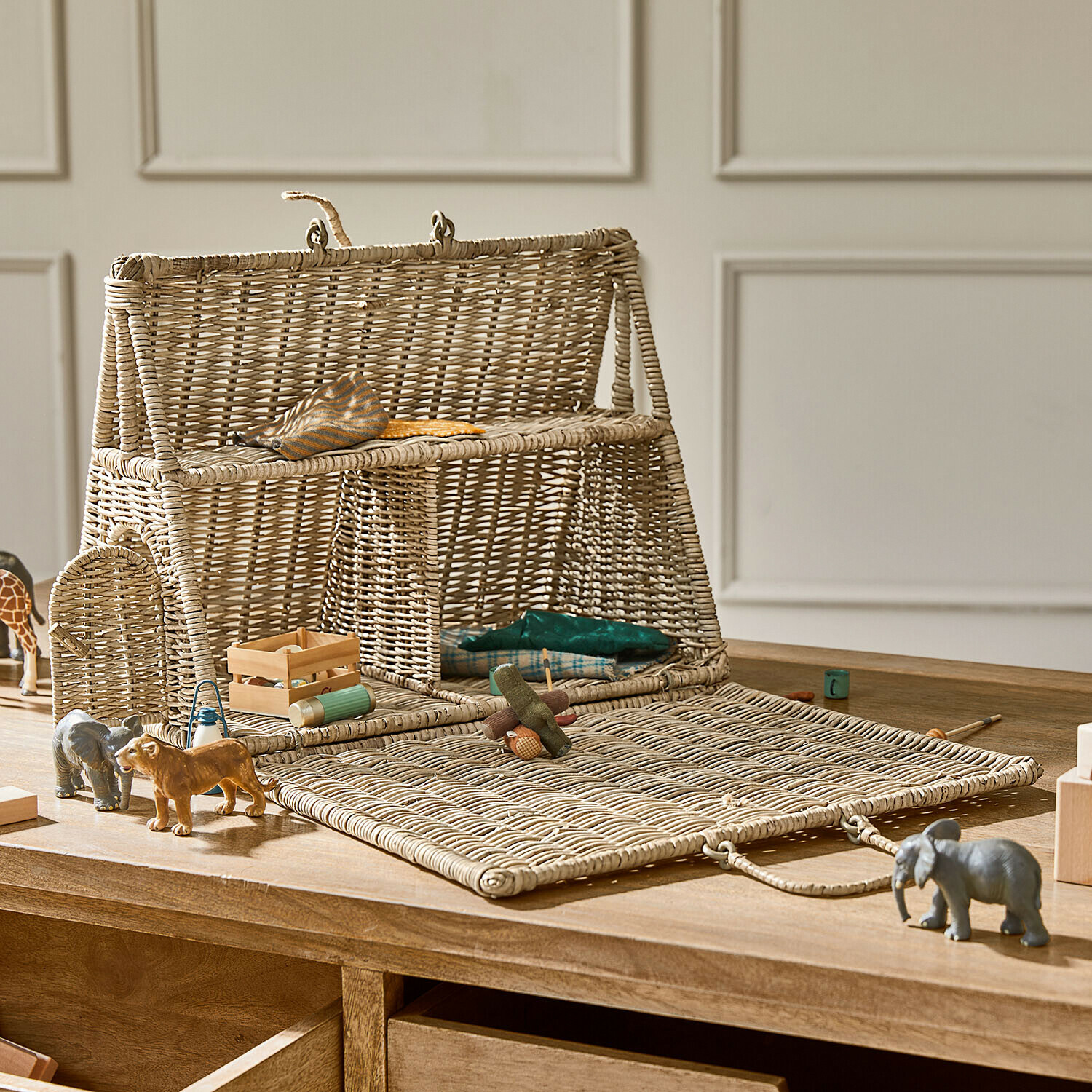 Natuurlijke rieten poppenhuis met opklapbare voorkant en houten speelgoed op tafel