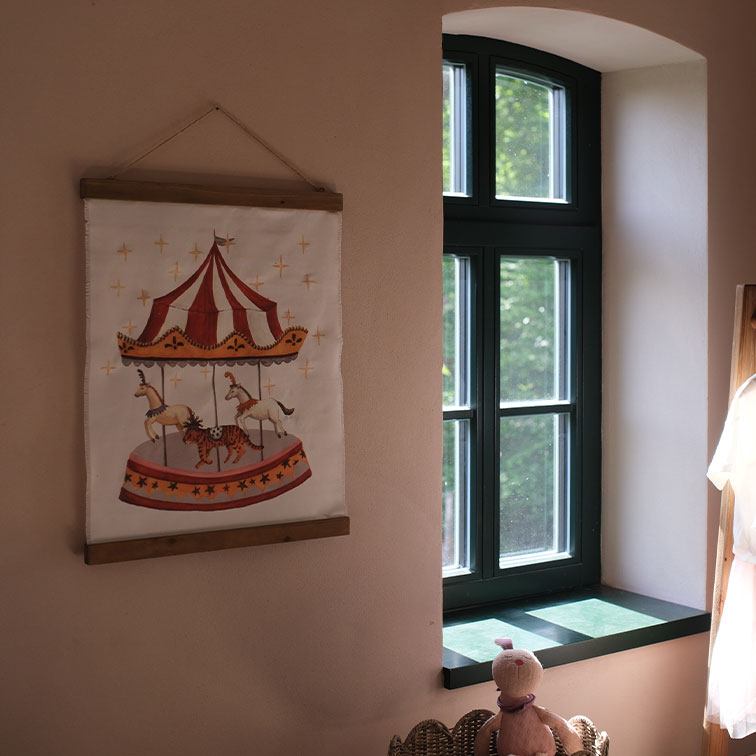 Decoratief stoffen schilderij met carrousel en dieren in een warme kinderkamer bij het raam