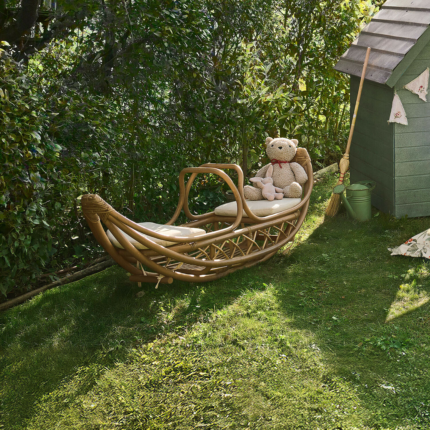 Rotan ligstoel in natuurlijke kleur met lichte kussens op gras in de tuin