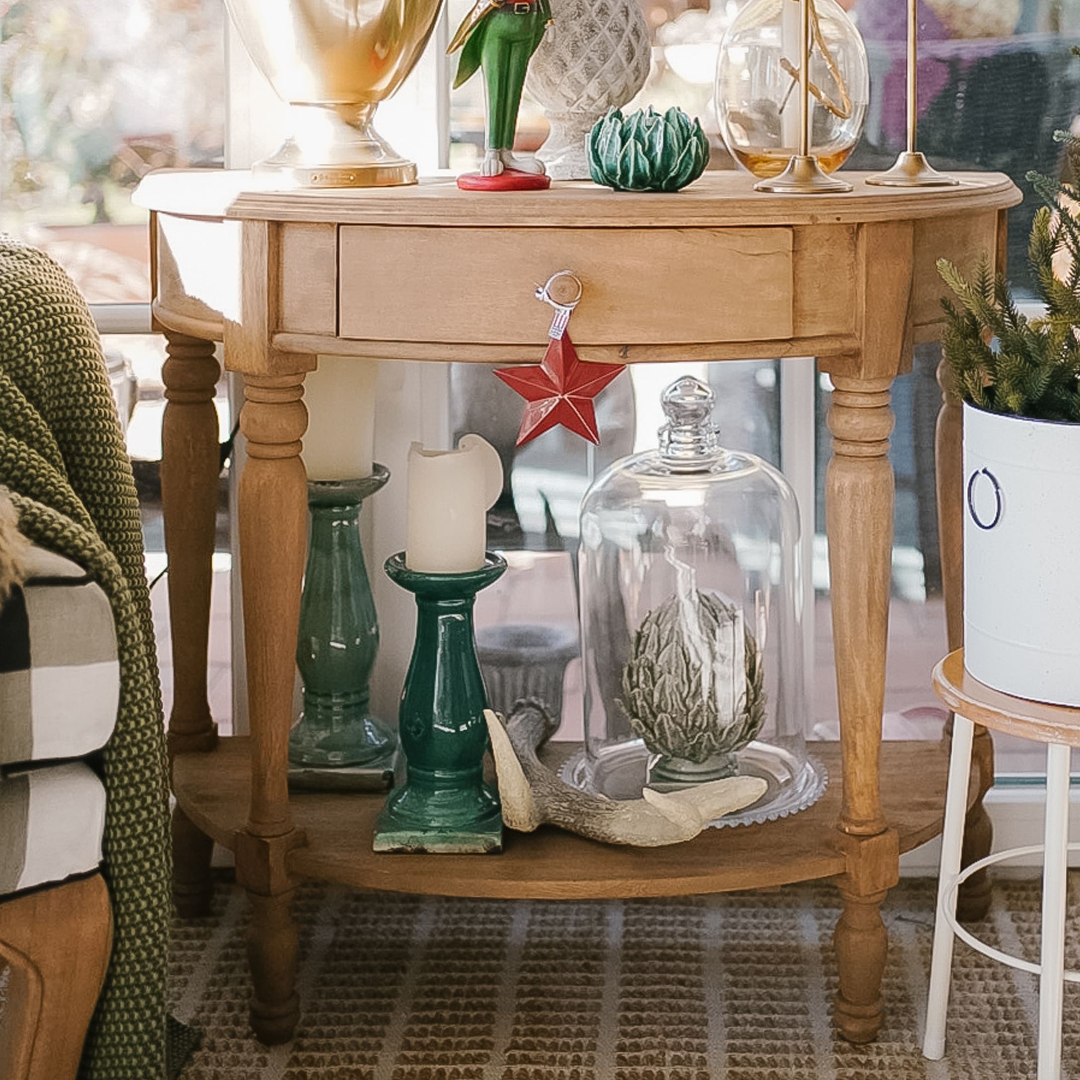 Houten tafel met kerstdecoraties, groene kandelaar en glazen stolp met decoratie