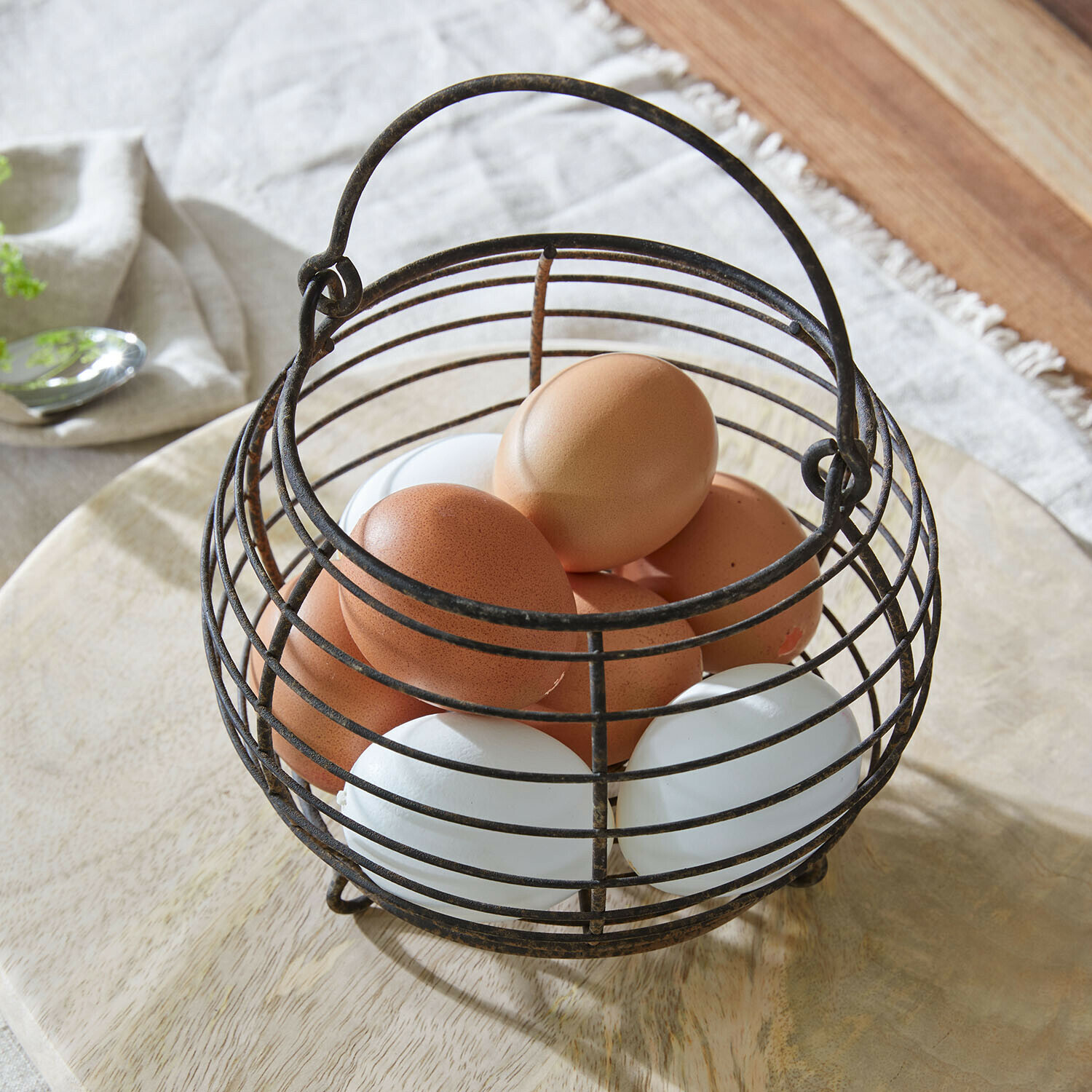 Vintage metalen eiermand met bruine en witte eieren op een lichte houten ondergrond