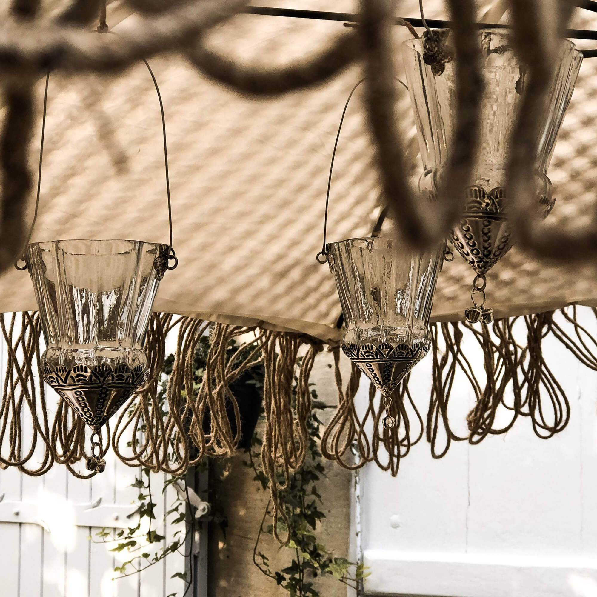 Glazen lantaarns met metalen versieringen en hangende touwen in boho-stijl, tuindecoratie