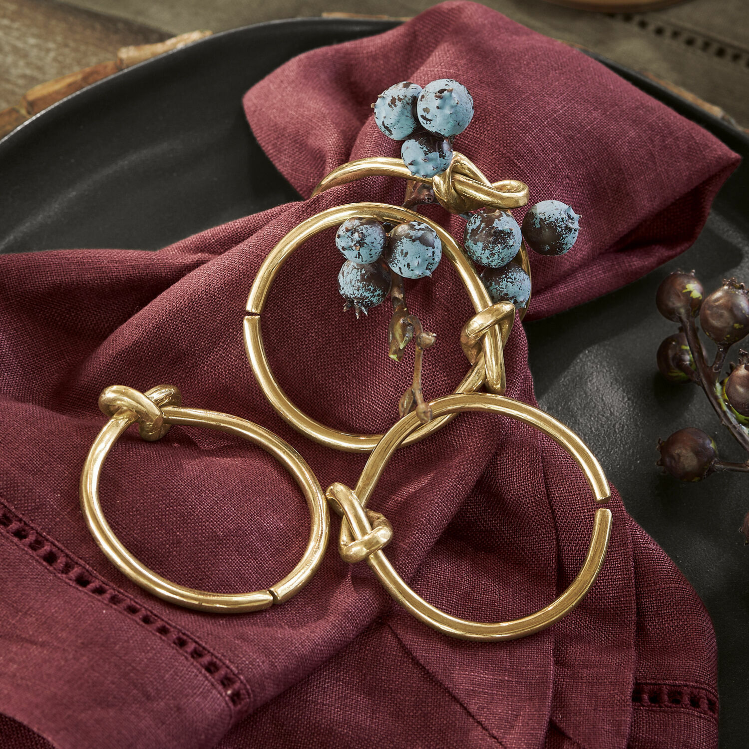 Servetring set van 4 Motje Set van drie gouden metalen ringen op bordeaux linnen doek met decoratieve bessen