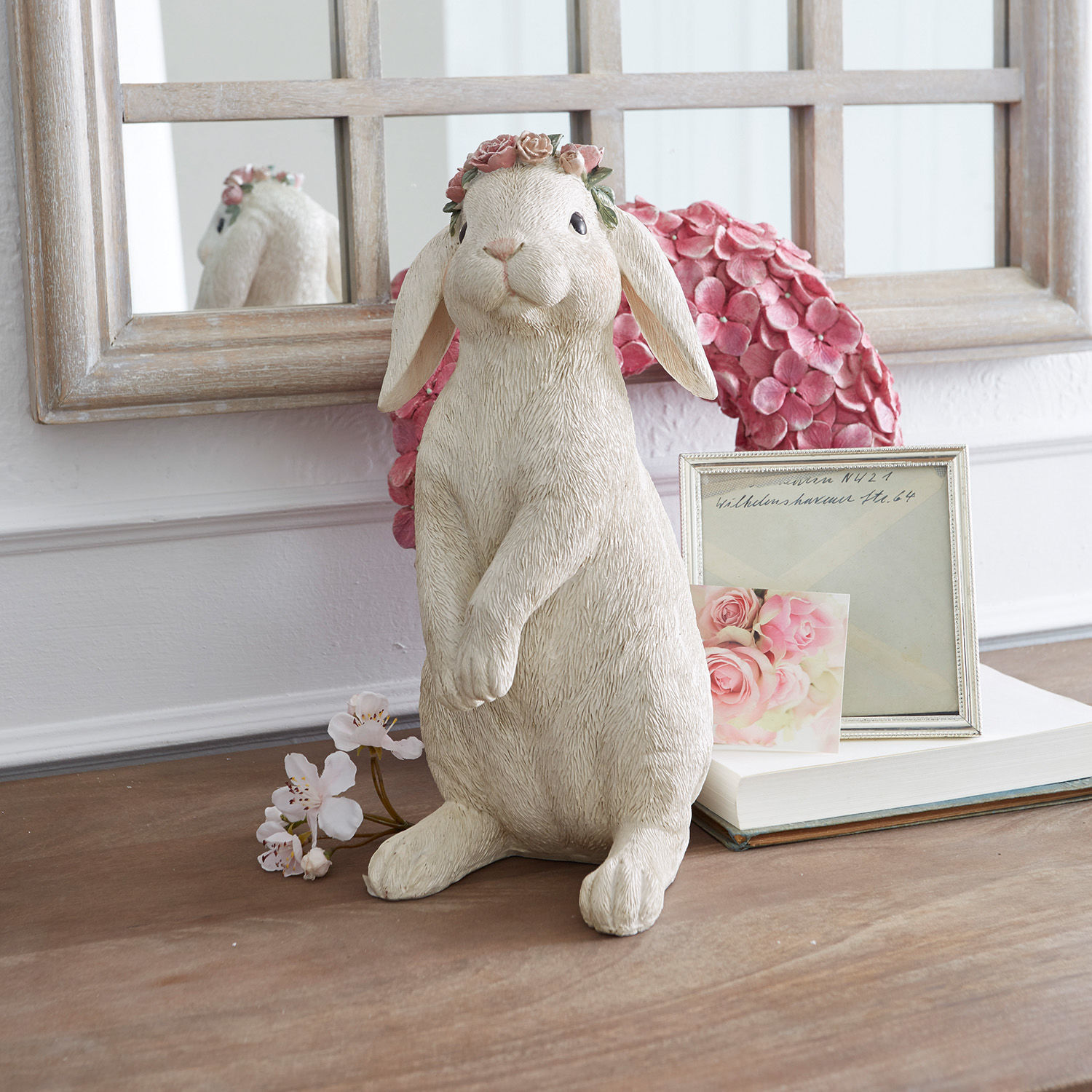 Haasje Sweety Konijnenfiguur van crèmekleurig materiaal met roze bloemenkrans op gedecoreerde tafel