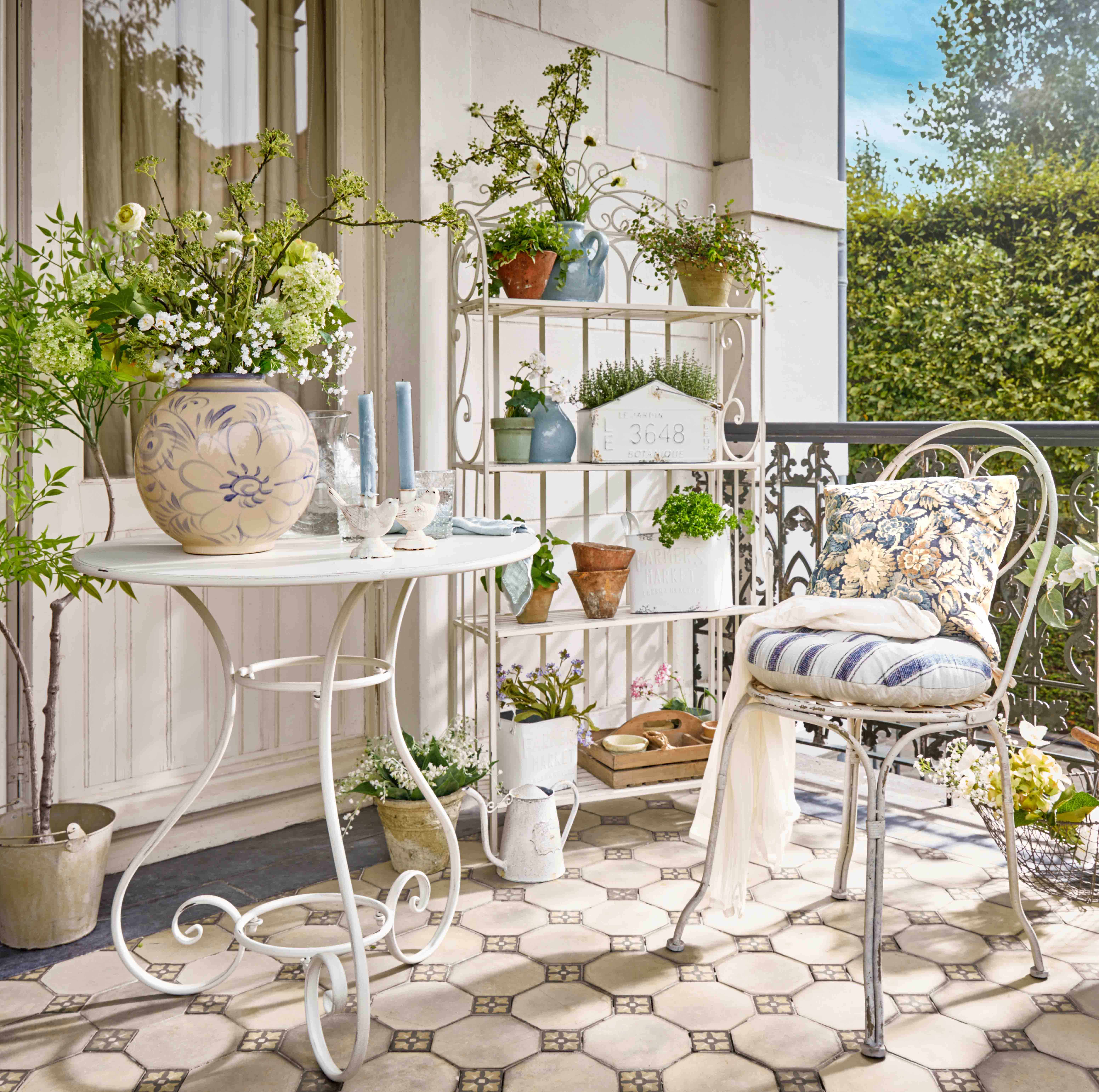 Witte metalen plank met planten in potten en decoratieve kaarsen op een bloementerras