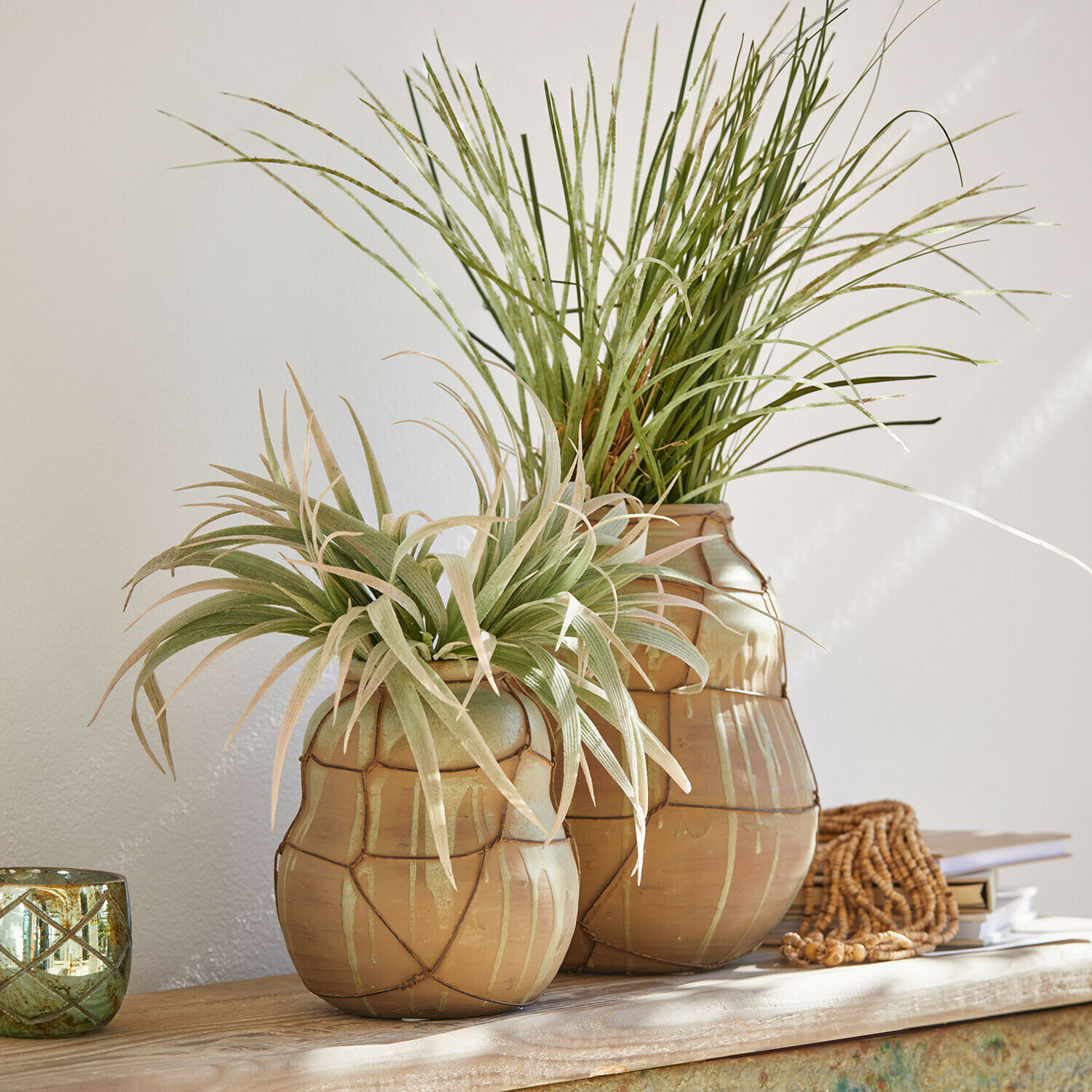 Vaas set van 2 Frandoro Twee beige keramische vazen met groene decoratieve planten op een lichte houten tafel