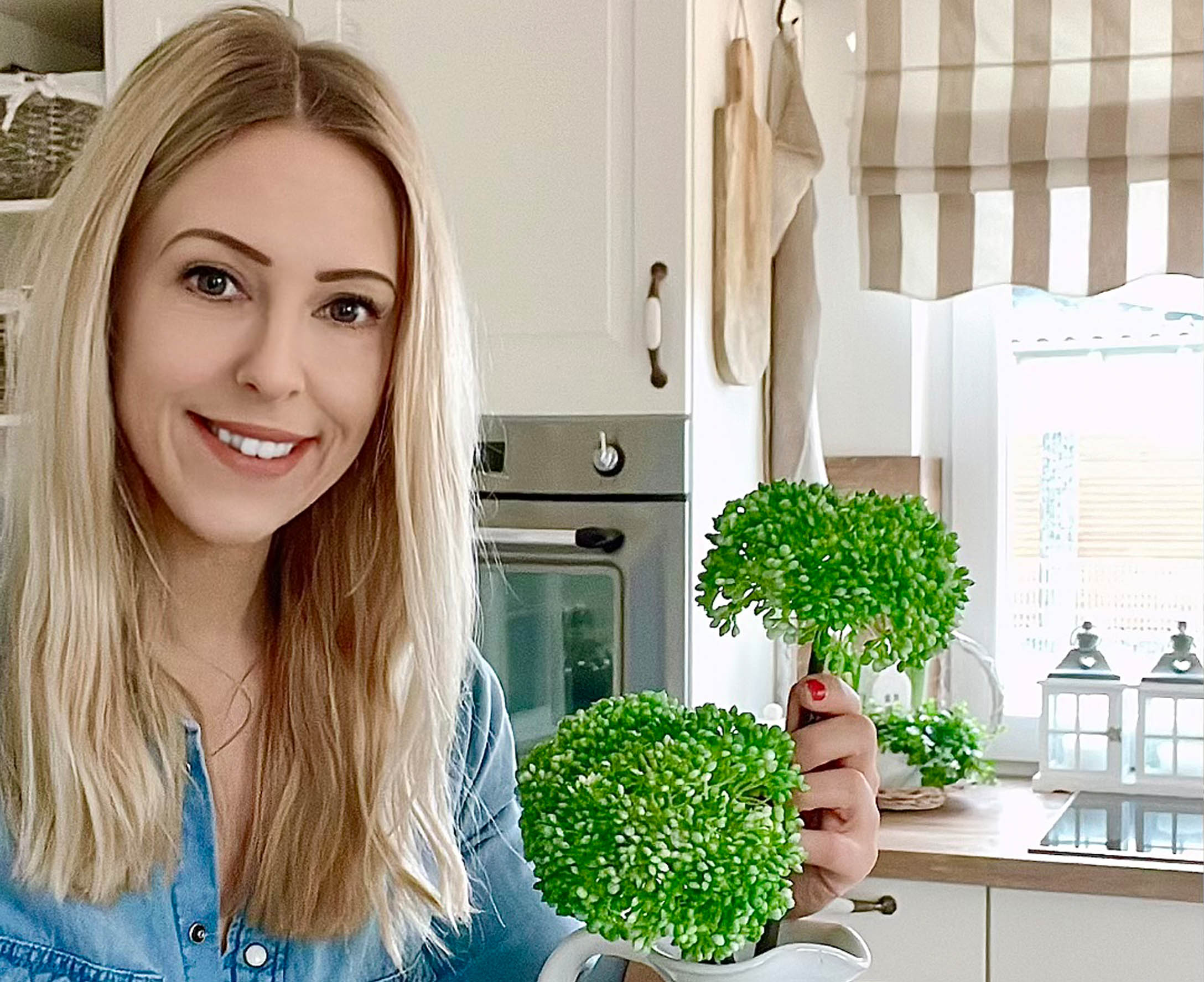 Vrouw in keuken met groene decoratieve bloemen in witte kan, rustieke stijl
