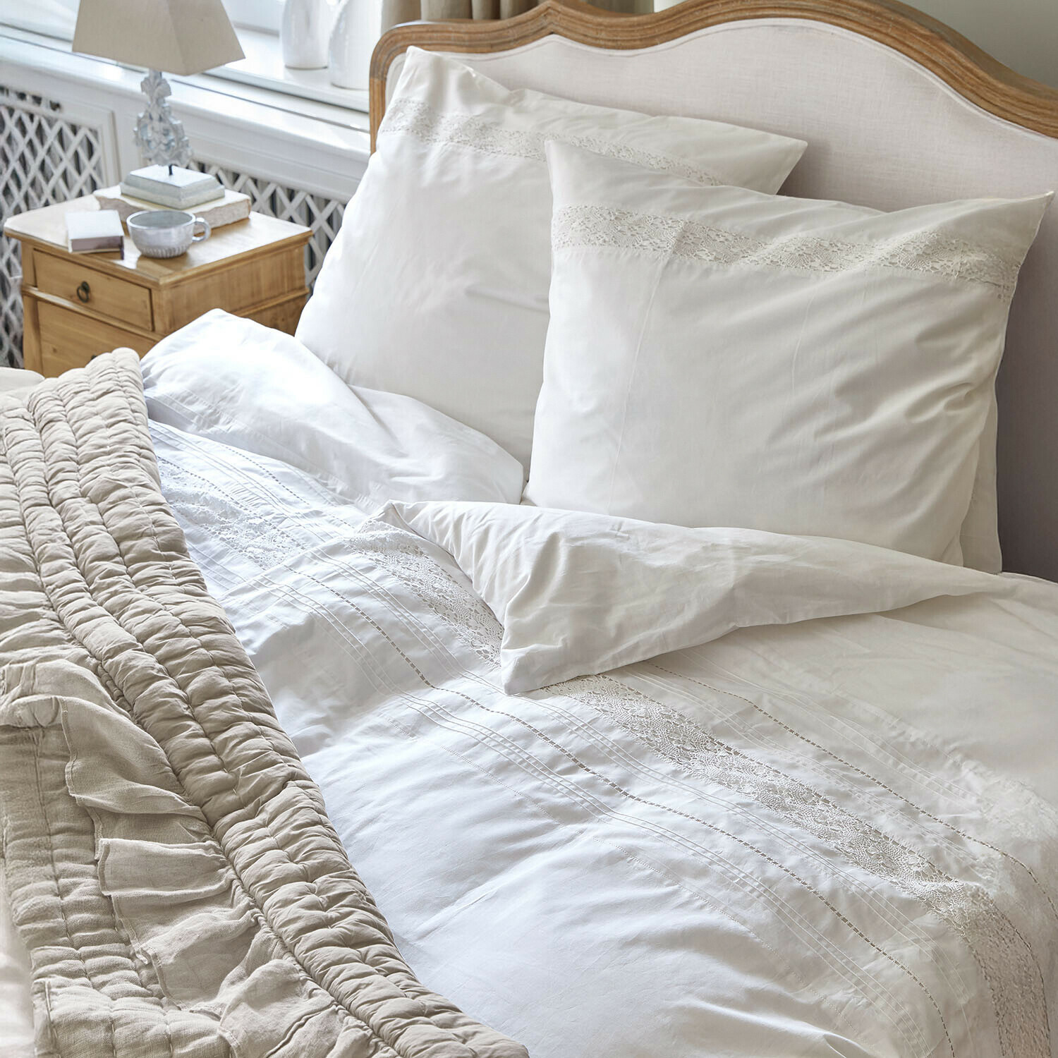 Witte beddengoed met kant op een houten bed met beige deken