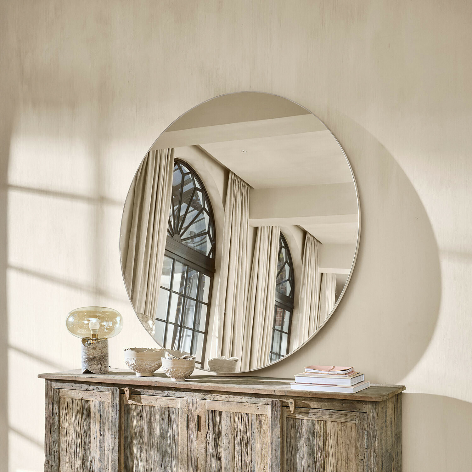 Spiegel Roulène Grote ronde spiegel aan de muur boven een houten dressoir in een lichte, natuurlijke ruimte