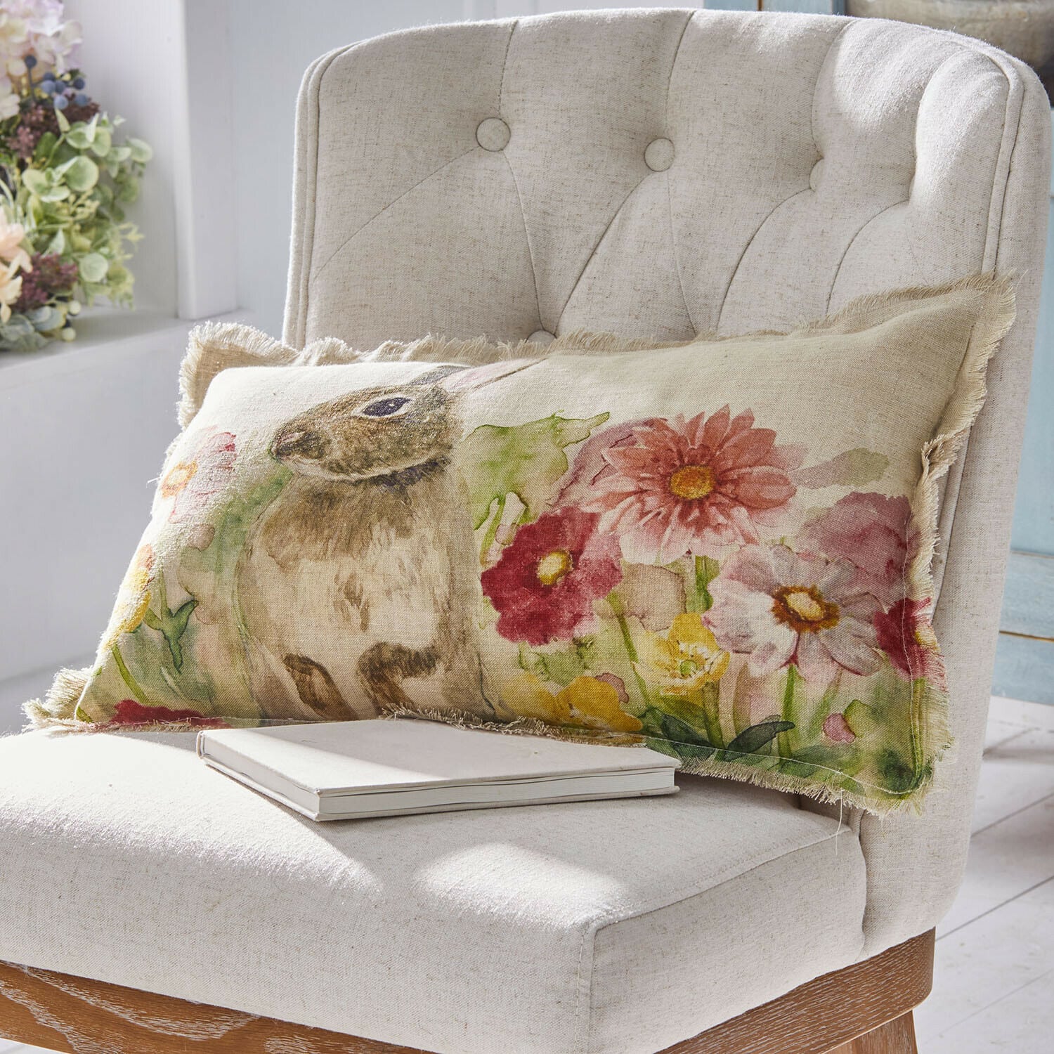 Kussenhoes Parélys Lang linnen kussen met konijn- en bloemenprint in pasteltinten op lichte stoel