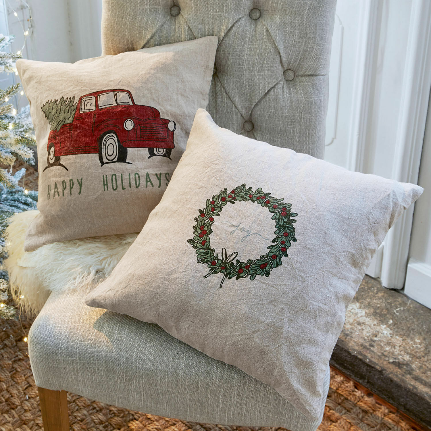 Linnen sierkussens met kerstmotieven in natuurlijke kleuren op een grijze stoel