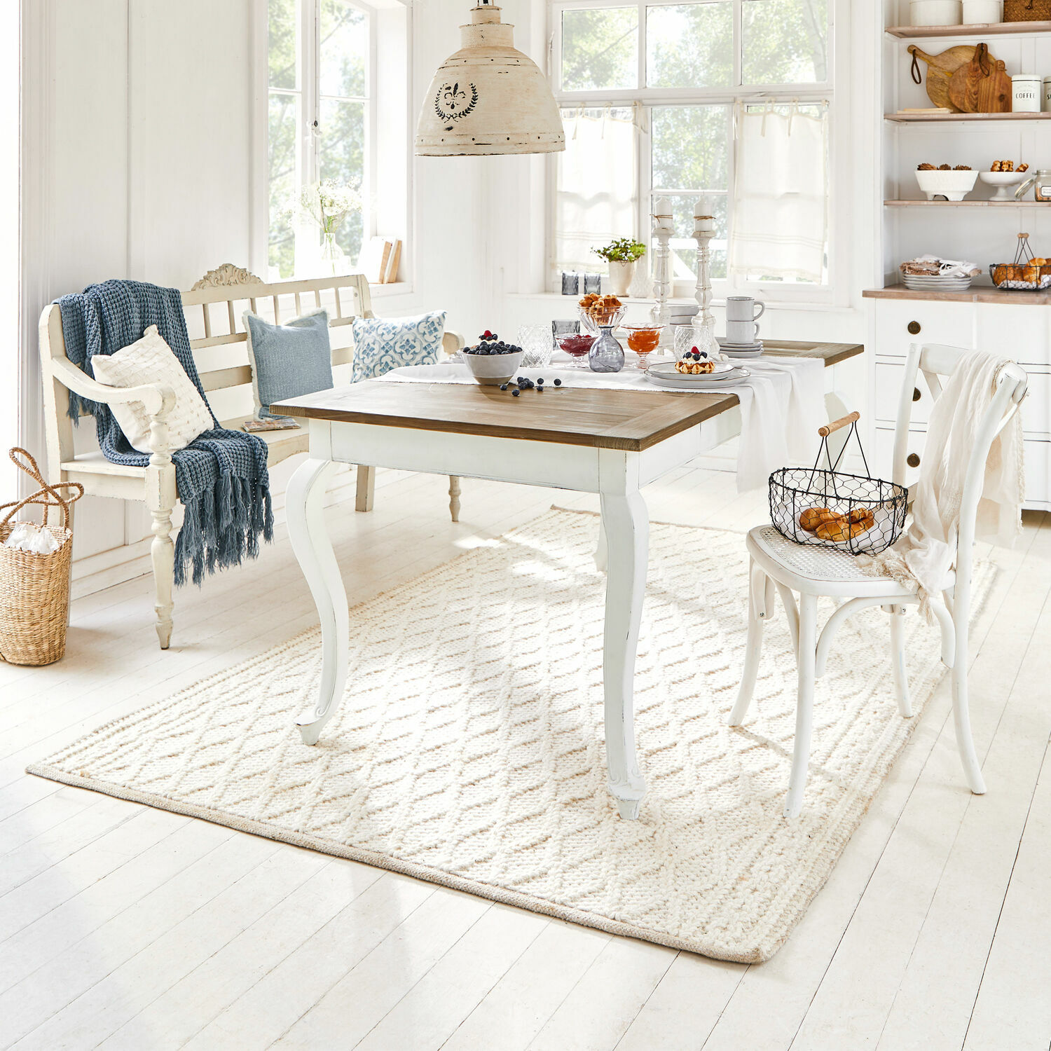 Vloerkleed Poloma Lichte houten tafel met witte onderstel en natuurlijk blad in gezellige eetkamer met decoratie