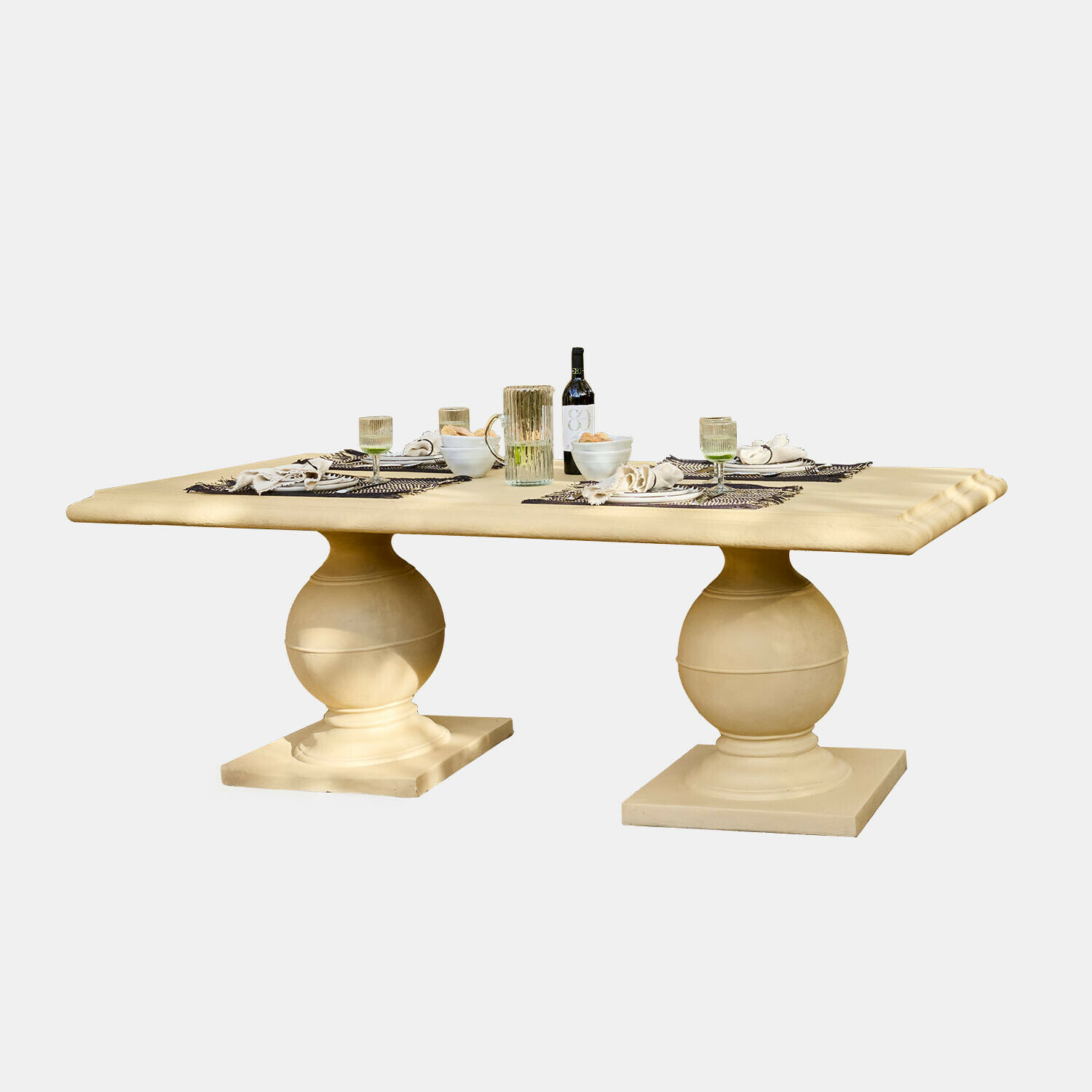 Tafel Talvero Grote eettafel van beige steen met twee bolvormige poten en gedekte tafel