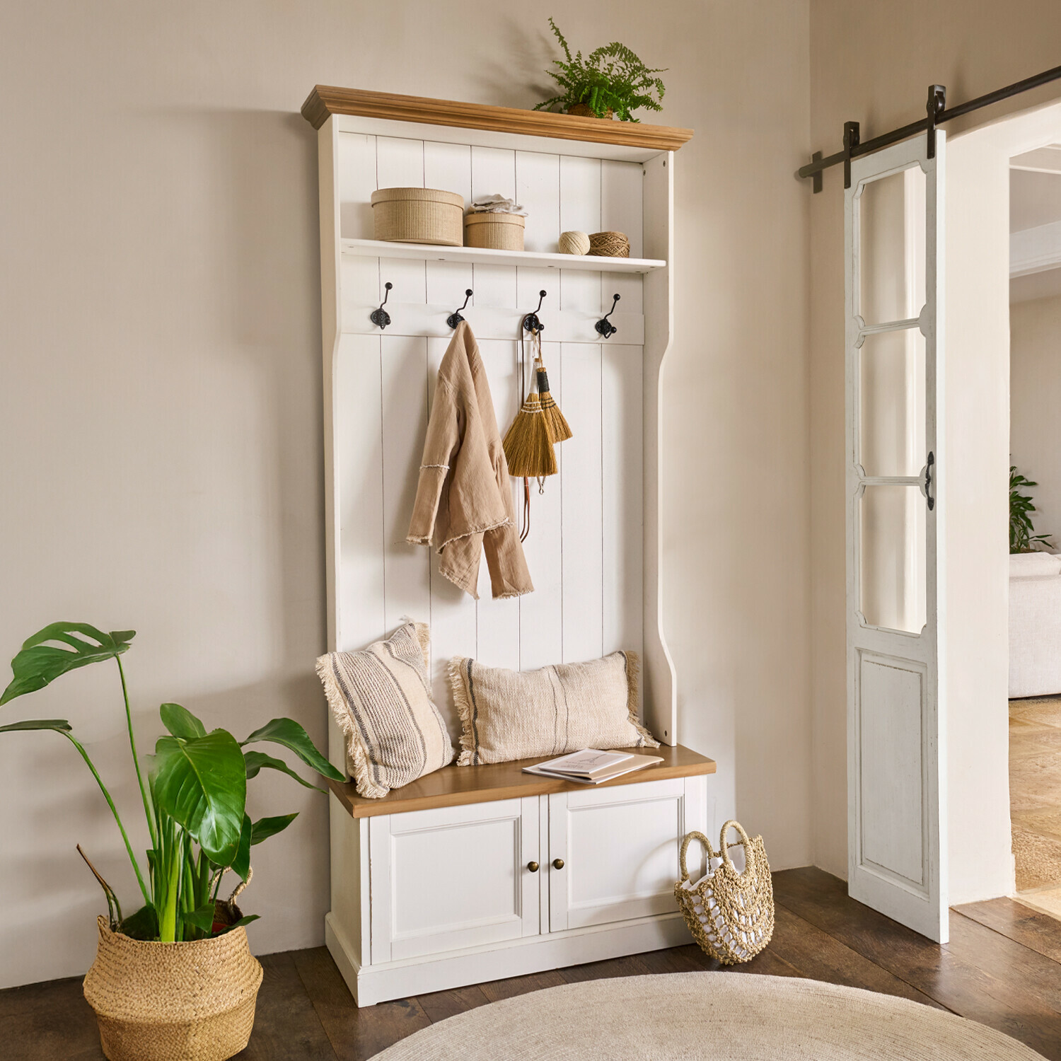 Witte houten halmeubel met zitbank, haken, beige kussens en natuurlijke decoratie met groene plant