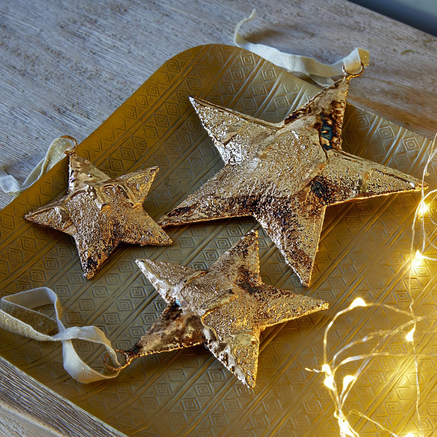 Hanger set van 3 Myrska Set van drie gouden metalen sterren als decoratie op een gouden dienblad met LED-lichtjes