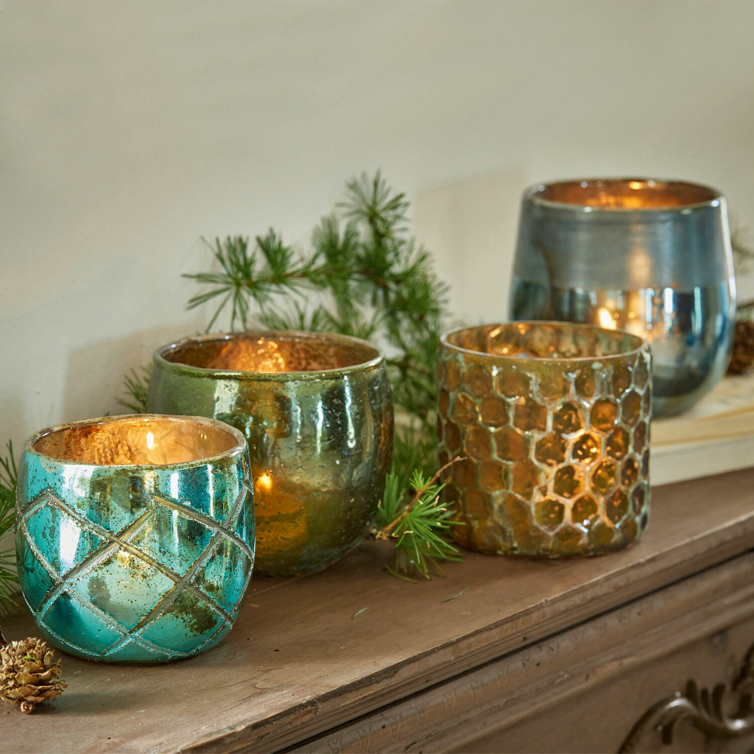 Windlicht set van 4 Marine Set van vier glazen theelichthouders in turquoise, groen en goud op een houten plank
