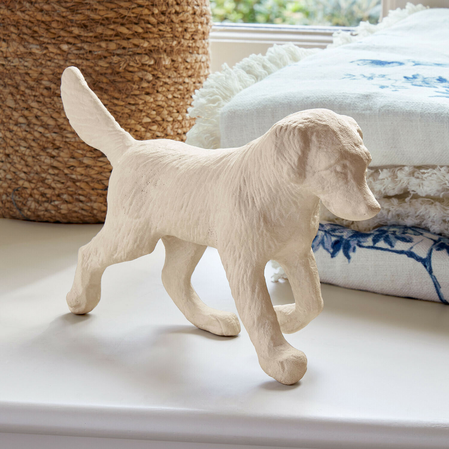 Decoratieve hond Wendrel Beige hondenfiguur van getextureerd materiaal op wit oppervlak met decoratieve stof op de achtergrond