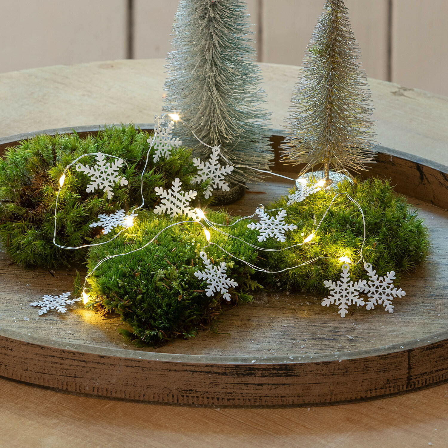Lichtsnoer Azmira Decoratieve LED-slinger met witte sneeuwvlokken op groen mos op houten dienblad