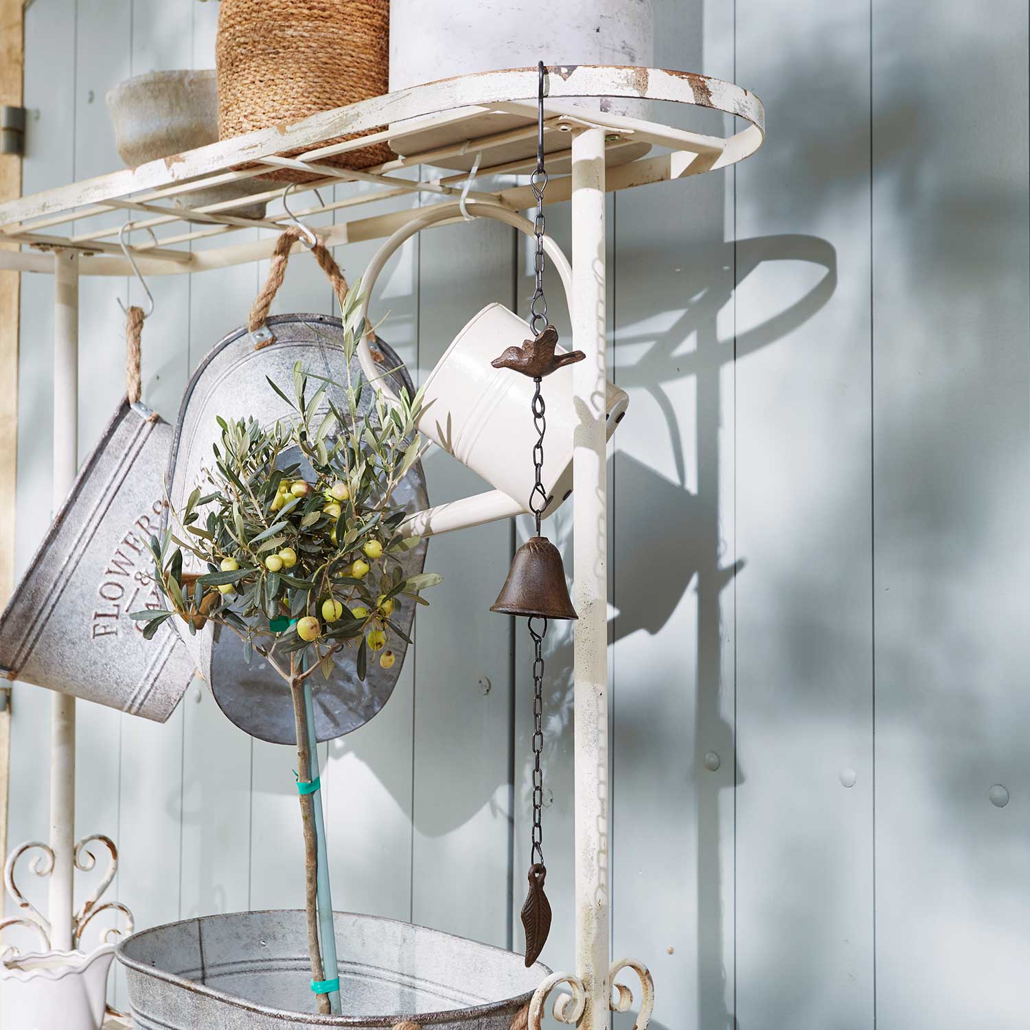 Metalen tuindecoratie met bel en vogel aan witte vintage frame