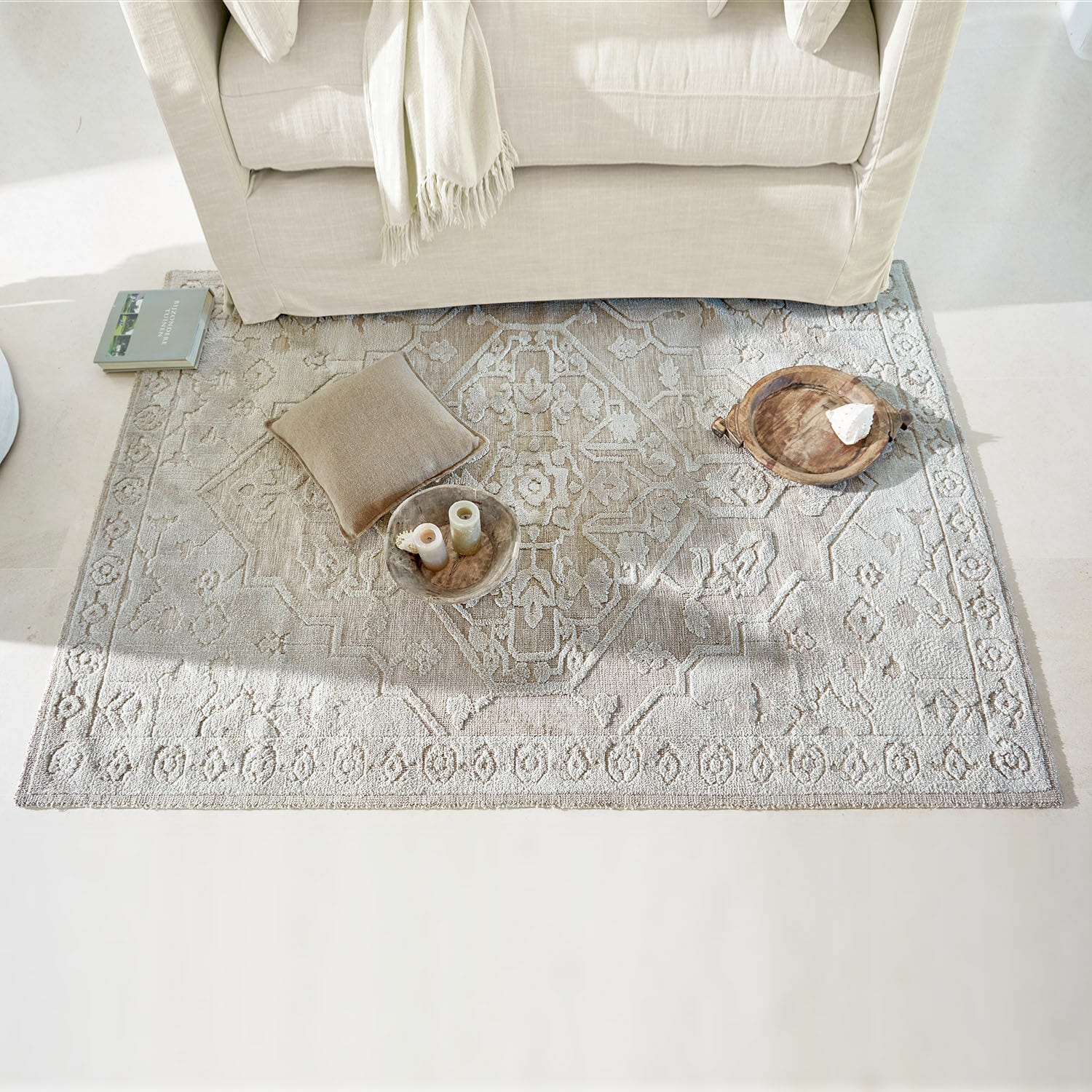 Vloerkleed Armidale Beige vloerkleed met fijn patroon onder lichte bank, kussen en decoraties op de vloer