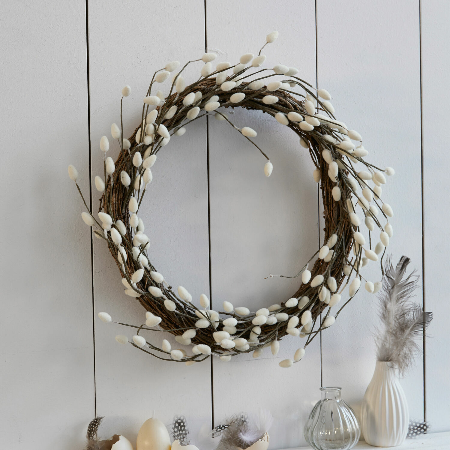 Krans Prapante Decoratieve krans van takken met witte, pluizige knoppen aan lichte muur, lentebehang