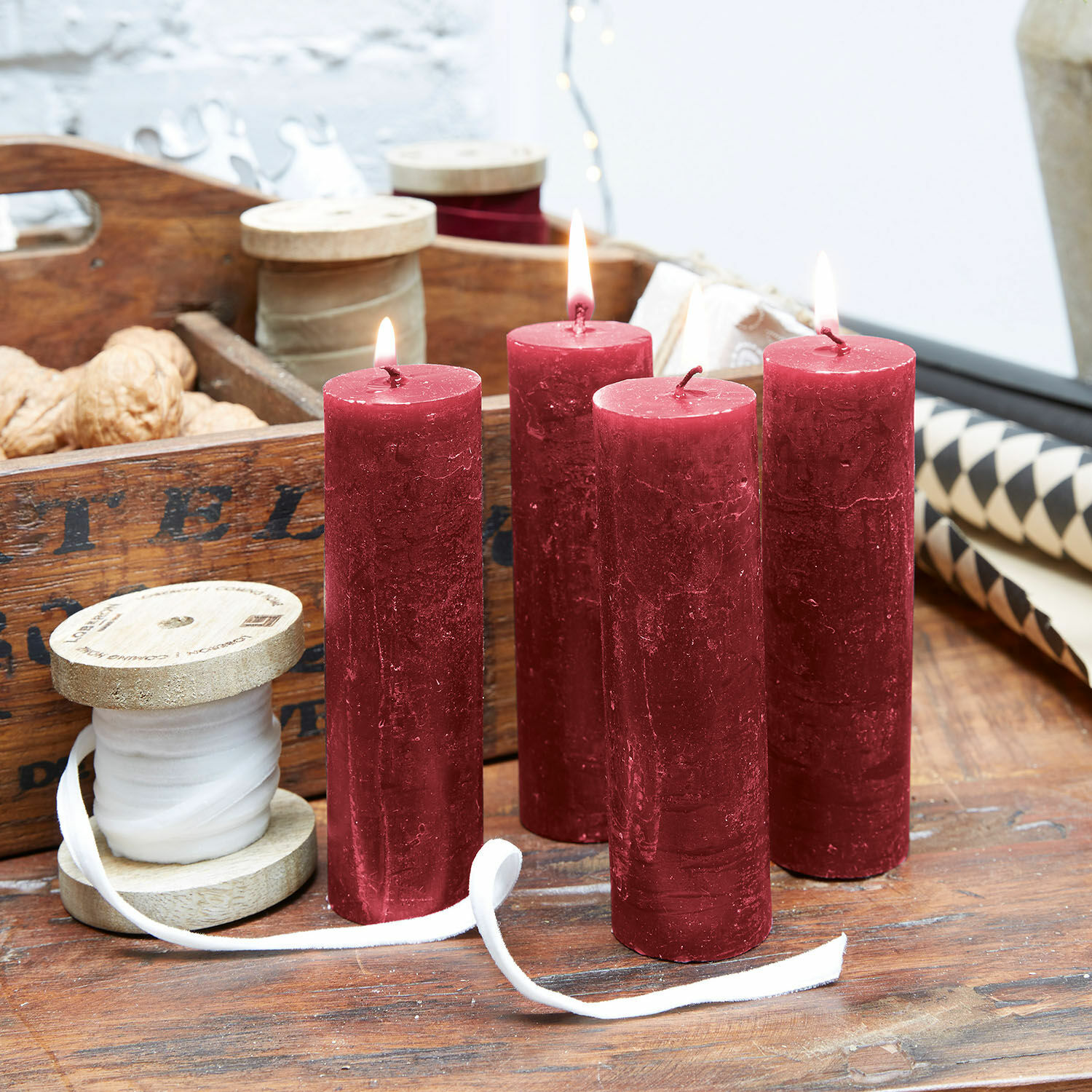 Kaars set van 4 Muriel Vier rode waskaarsen op houten tafel met decoratieve spoelen en walnoten