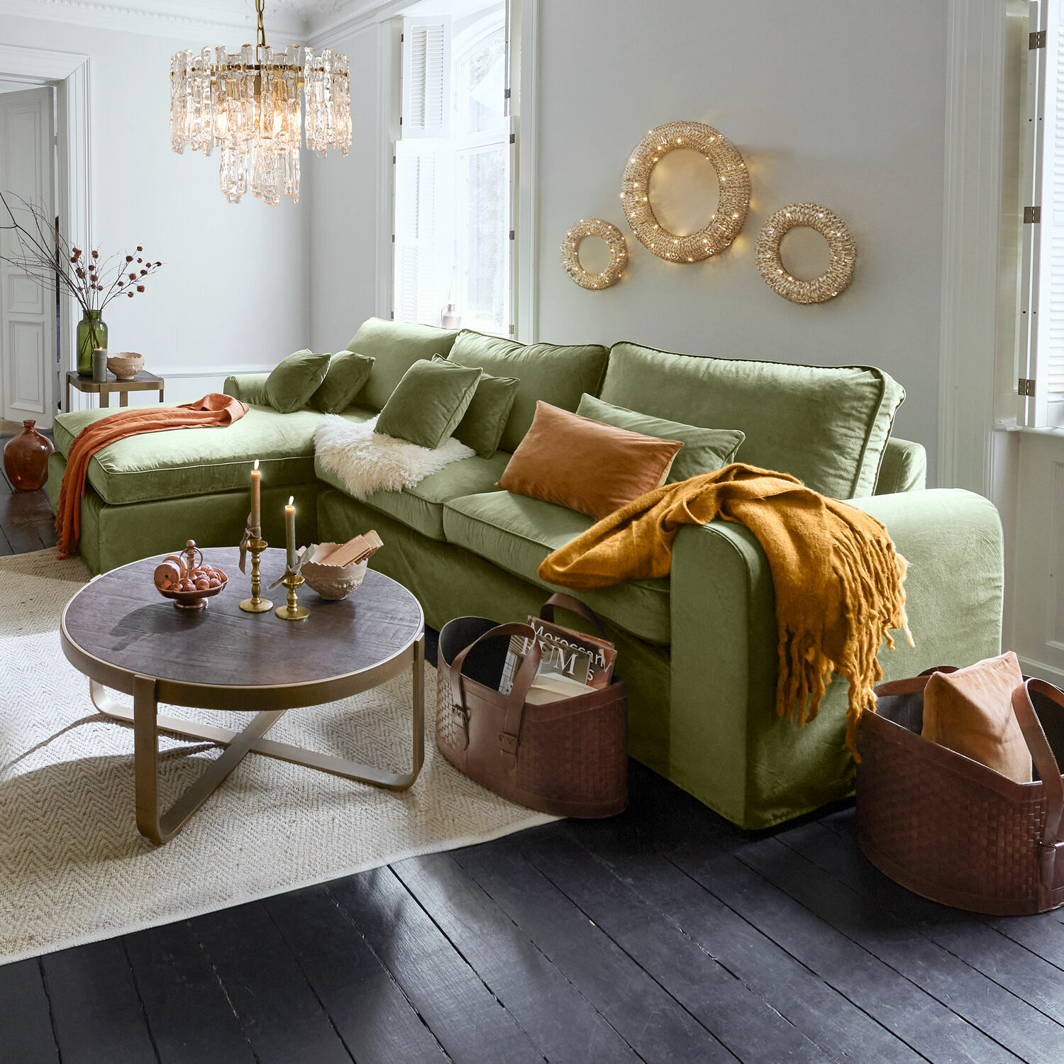 Bank Seaford Groene fluwelen bank met kussens en oranje deken in moderne woonkamer met decoratieve verlichting