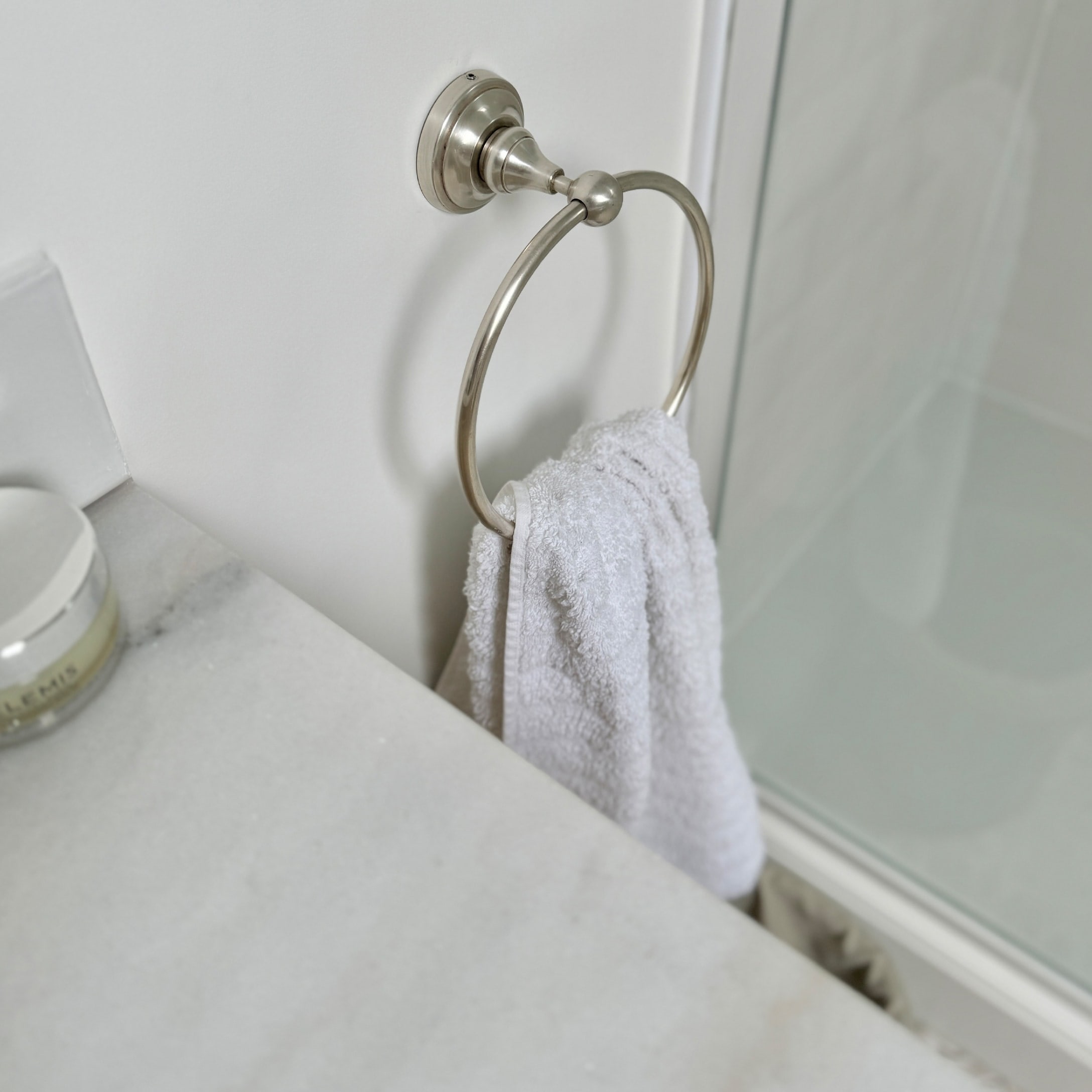 Metalen handdoekring met witte handdoek in badkamer met marmeren blad