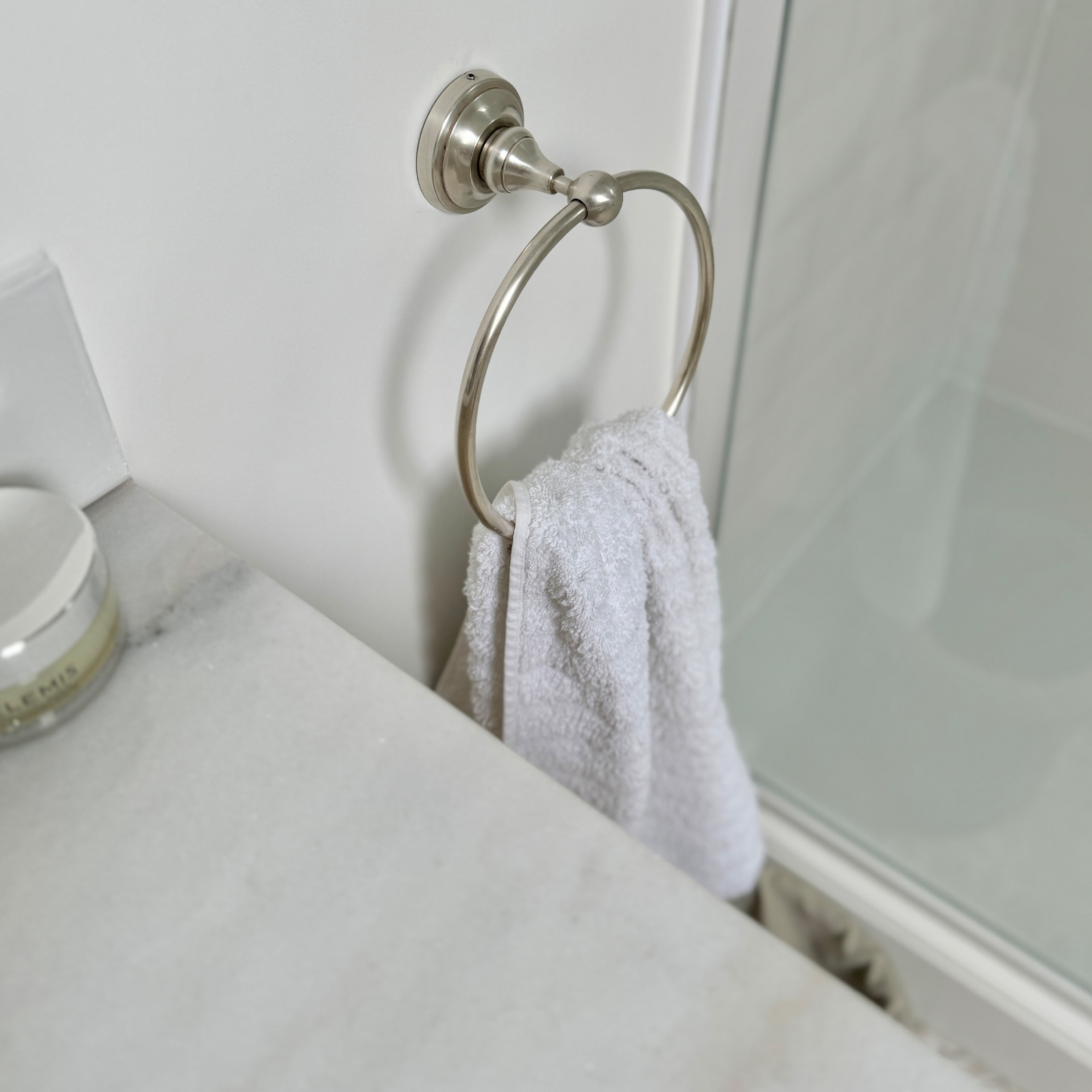 Metalen handdoekring met witte handdoek in badkamer met marmeren blad