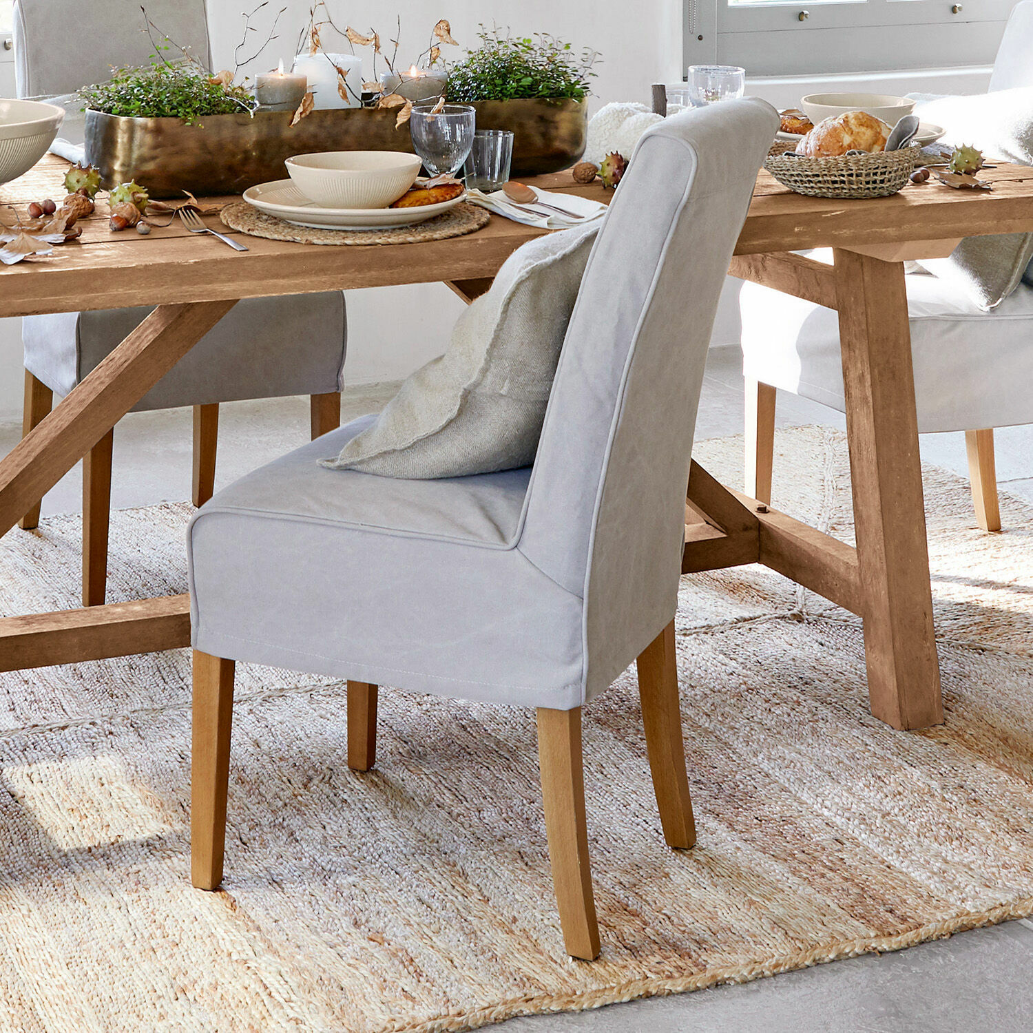 Grijze gestoffeerde stoel met houten poten bij houten eettafel in eetkamer