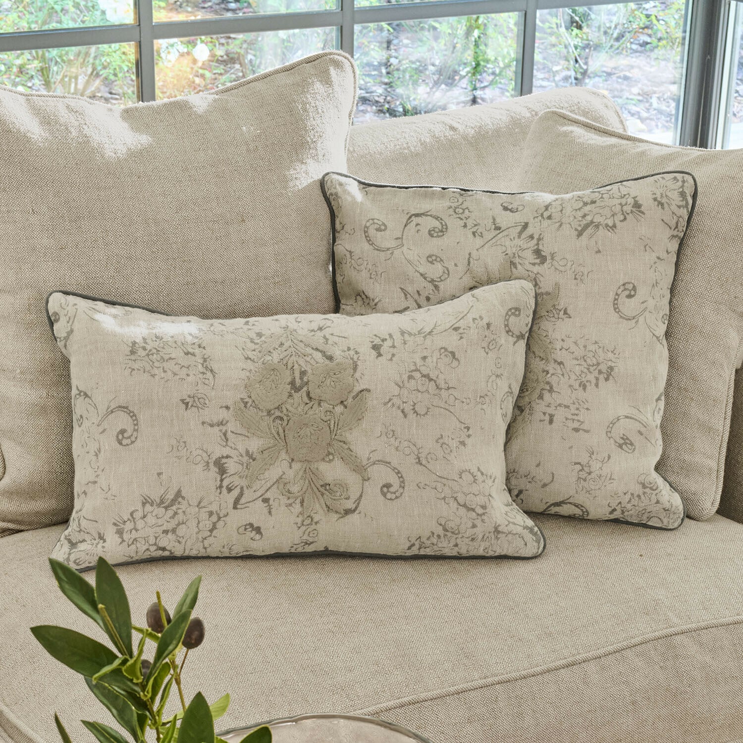 Beige linnen sierkussens met bloemmotief op lichte bank in woonkamer