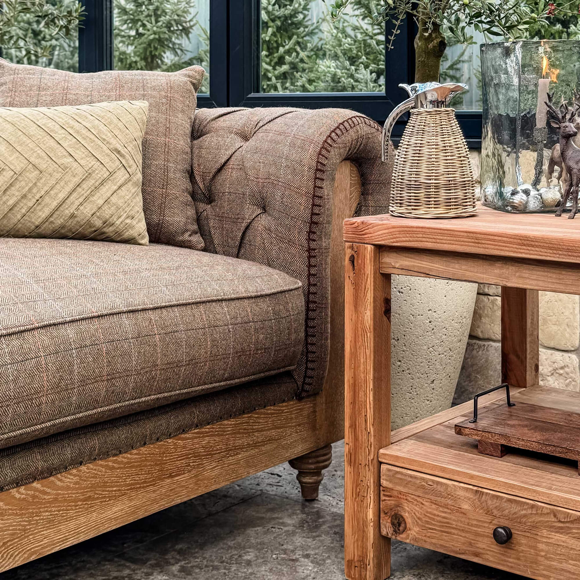Bruine gestoffeerde bank met houten frame en beige kussen naast rustieke houten tafel