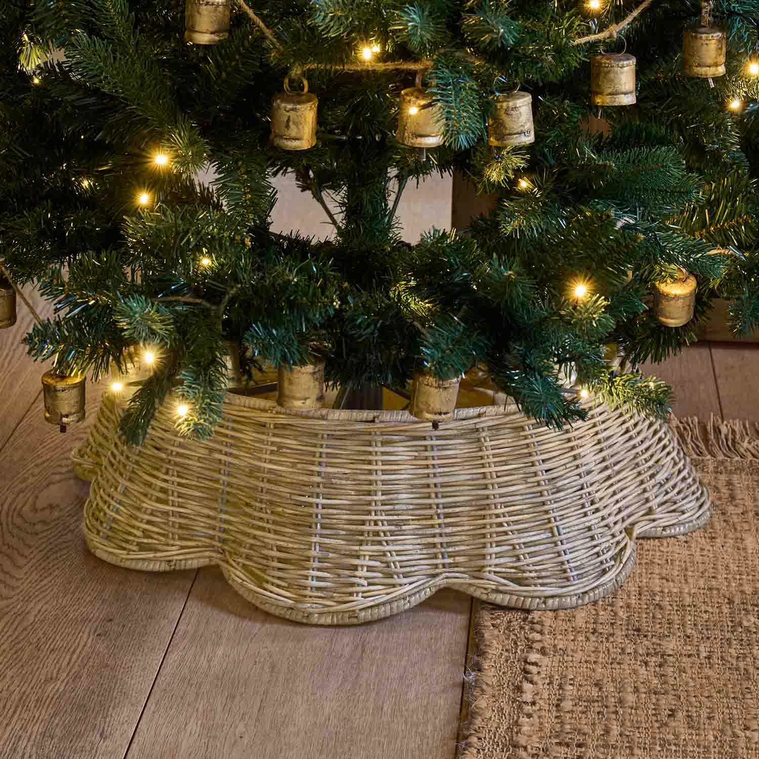 Natuurlijke lichtbruine rieten boomstandaard onder een groene kerstboom met warme lichtjes