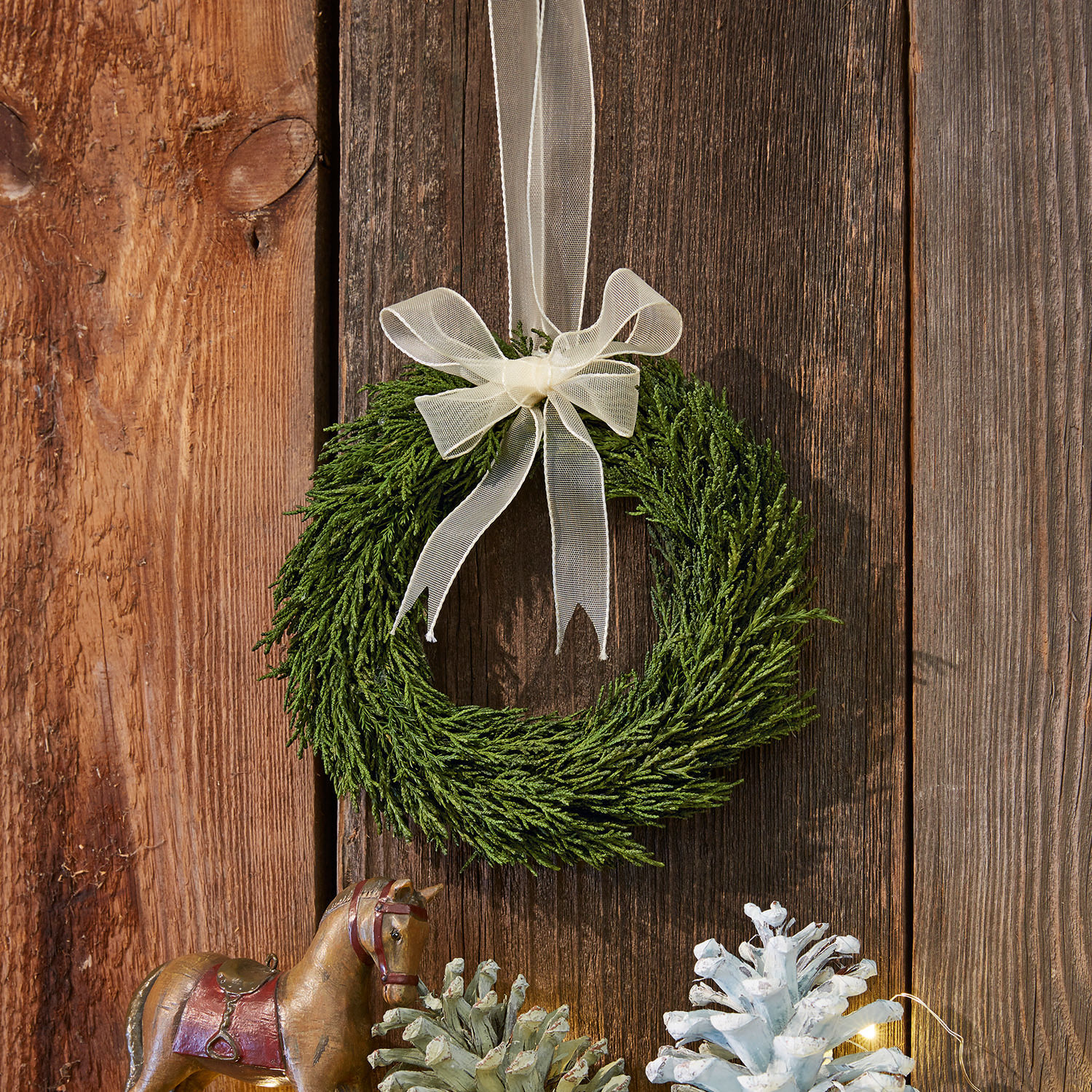 Krans Sare Groene takkenkrans met crèmekleurige strik aan houten achtergrond, kerstdecoratie