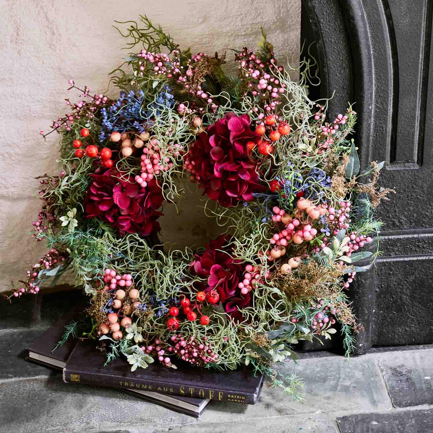 Decoratieve krans met rode bloemen en gekleurde bessen voor deur, seizoensdecoratie