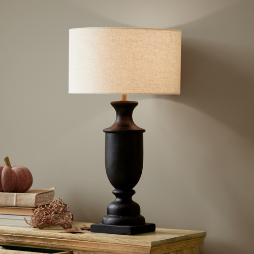 Zwarte keramische tafellamp met beige kap op houten tafel, interieurdecoratie